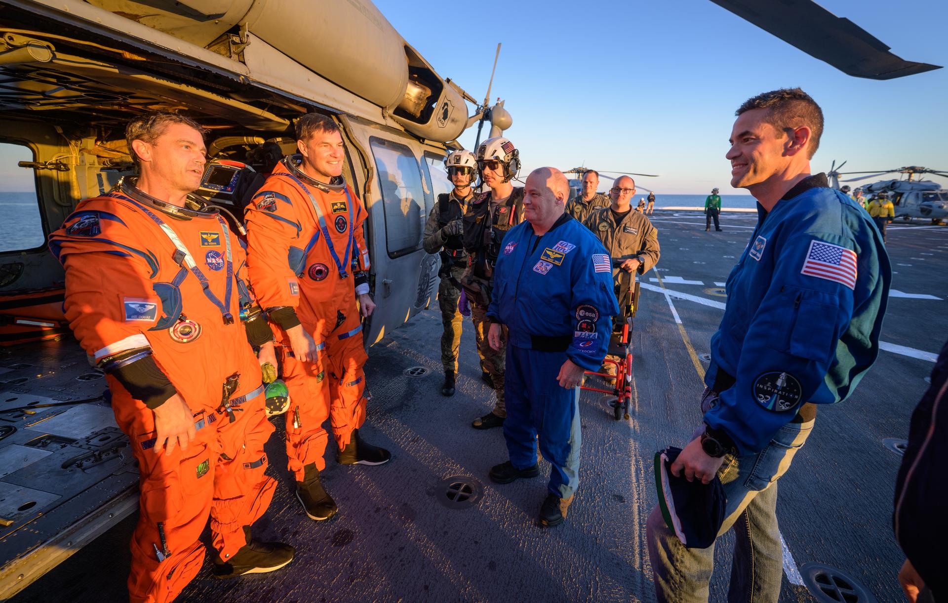 NASA astronaut Victor Glover, Artemis II pilot, left, and CSA (Canadian Space Agency) astronaut Jeremy Hansen, Artemis II mission specialist, talk with NASA Administrator Jared Isaacman at their Navy MH-60 Seahawk from Helicopter Sea Combat Squadron (HSC) 23 on the flight deck of USS John P. Murtha after they and fellow crewmates NASA Astronauts Victor Glover, and Christina Koch were extracted from their Orion spacecraft after splashdown, Friday, April 10, 2026, in the Pacific Ocean off the coast of California. NASA’s Artemis II mission took the quartet on a nearly 10-day journey around the Moon and back to Earth. Following a splashdown at 5:07 p.m. PDT (8:07 p.m. EDT), NASA, U.S. Navy, and U.S. Air Force teams are working to bring the Orion spacecraft aboard the recovery ship. Photo Credit: (NASA/Bill Ingalls)