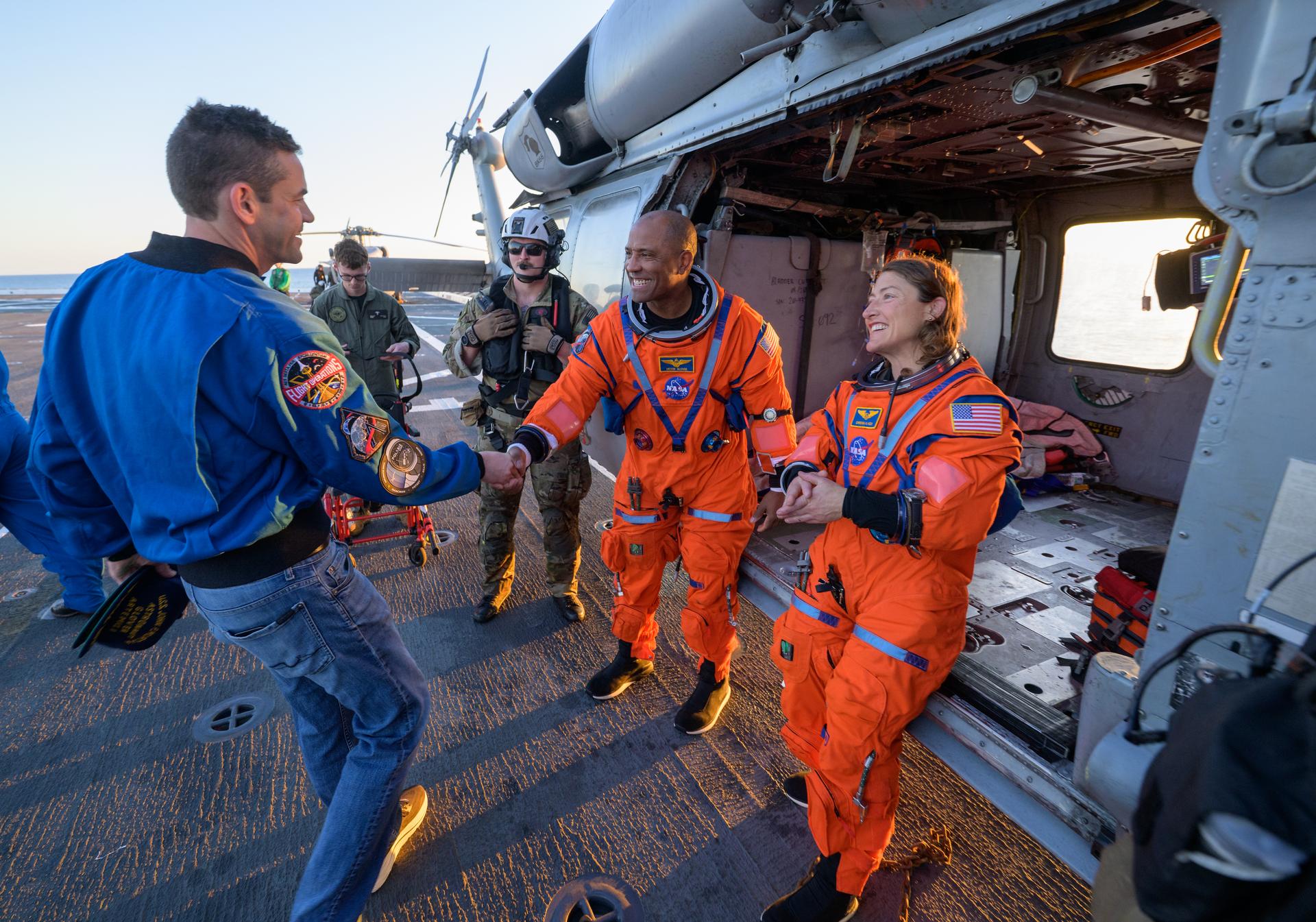 NASA astronaut Victor Glover, Artemis II pilot, left, and NASA astronaut Christina Koch, Artemis II mission specialist, talk with NASA Administrator Jared Isaacman at their Navy MH-60 Seahawk from Helicopter Sea Combat Squadron (HSC) 23 on the flight deck of USS John P. Murtha after they and fellow crewmates NASA Astronauts Victor Glover, and Christina Koch were extracted from their Orion spacecraft after splashdown, Friday, April 10, 2026, in the Pacific Ocean off the coast of California. NASA’s Artemis II mission took the quartet on a nearly 10-day journey around the Moon and back to Earth. Following a splashdown at 5:07 p.m. PDT (8:07 p.m. EDT), NASA, U.S. Navy, and U.S. Air Force teams are working to bring the Orion spacecraft aboard the recovery ship. Photo Credit: (NASA/Bill Ingalls)