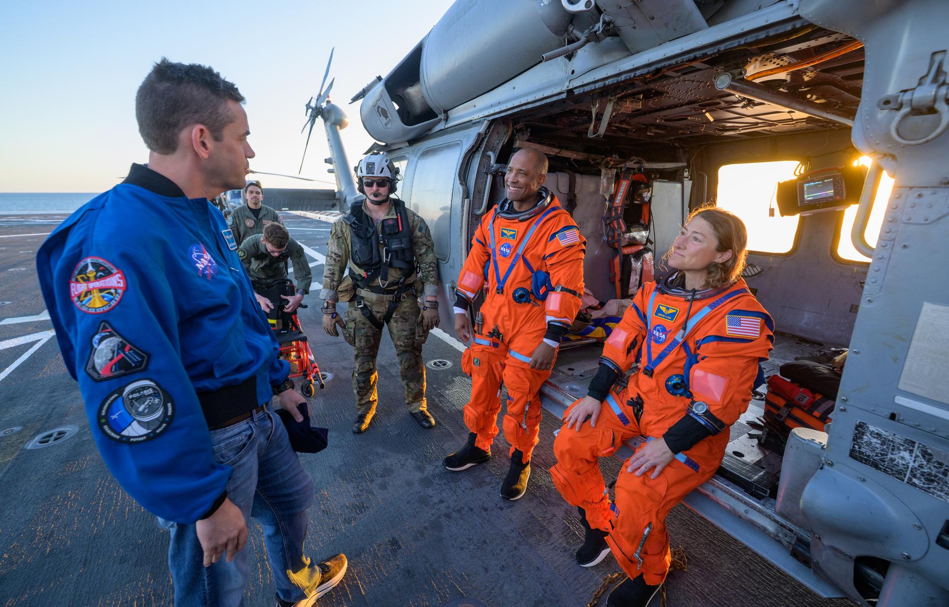 NASA astronaut Victor Glover, Artemis II pilot, left, and NASA astronaut Christina Koch, Artemis II mission specialist, talk with NASA Administrator Jared Isaacman at their Navy MH-60 Seahawk from Helicopter Sea Combat Squadron (HSC) 23 on the flight deck of USS John P. Murtha after they and fellow crewmates NASA Astronauts Victor Glover, and Christina Koch were extracted from their Orion spacecraft after splashdown, Friday, April 10, 2026, in the Pacific Ocean off the coast of California. NASA’s Artemis II mission took the quartet on a nearly 10-day journey around the Moon and back to Earth. Following a splashdown at 5:07 p.m. PDT (8:07 p.m. EDT), NASA, U.S. Navy, and U.S. Air Force teams are working to bring the Orion spacecraft aboard the recovery ship. Photo Credit: (NASA/Bill Ingalls)