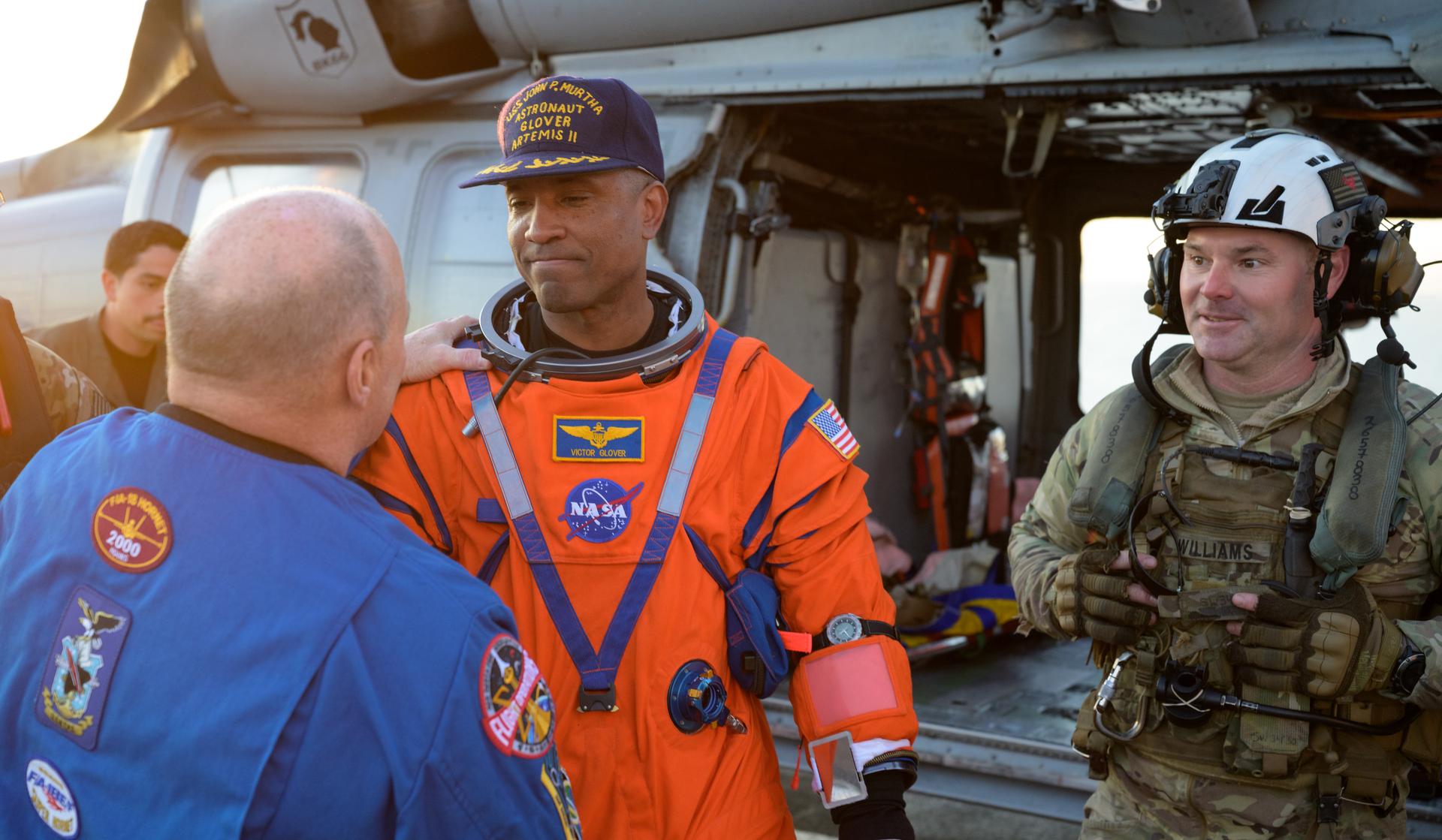 NASA astronaut Victor Glover, Artemis II pilot shakes hands with Scott Tingle, Chief of the Astronaut Office as he is assisted from a Navy MH-60 Seahawk from Helicopter Sea Combat Squadron (HSC) 23 on the flight deck of USS John P. Murtha after he and fellow crewmates NASA Astronauts Reid Wiseman,  Christina Koch, and CSA (Canadian Space Agency) astronaut Jeremy Hansen, Artemis II mission specialist were extracted from their Orion spacecraft after splashdown, Friday, April 10, 2026, in the Pacific Ocean off the coast of California. NASA’s Artemis II mission took the quartet on a nearly 10-day journey around the Moon and back to Earth. Following a splashdown at 5:07 p.m. PDT (8:07 p.m. EDT), NASA, U.S. Navy, and U.S. Air Force teams are working to bring the Orion spacecraft aboard the recovery ship. Photo Credit: (NASA/Bill Ingalls)