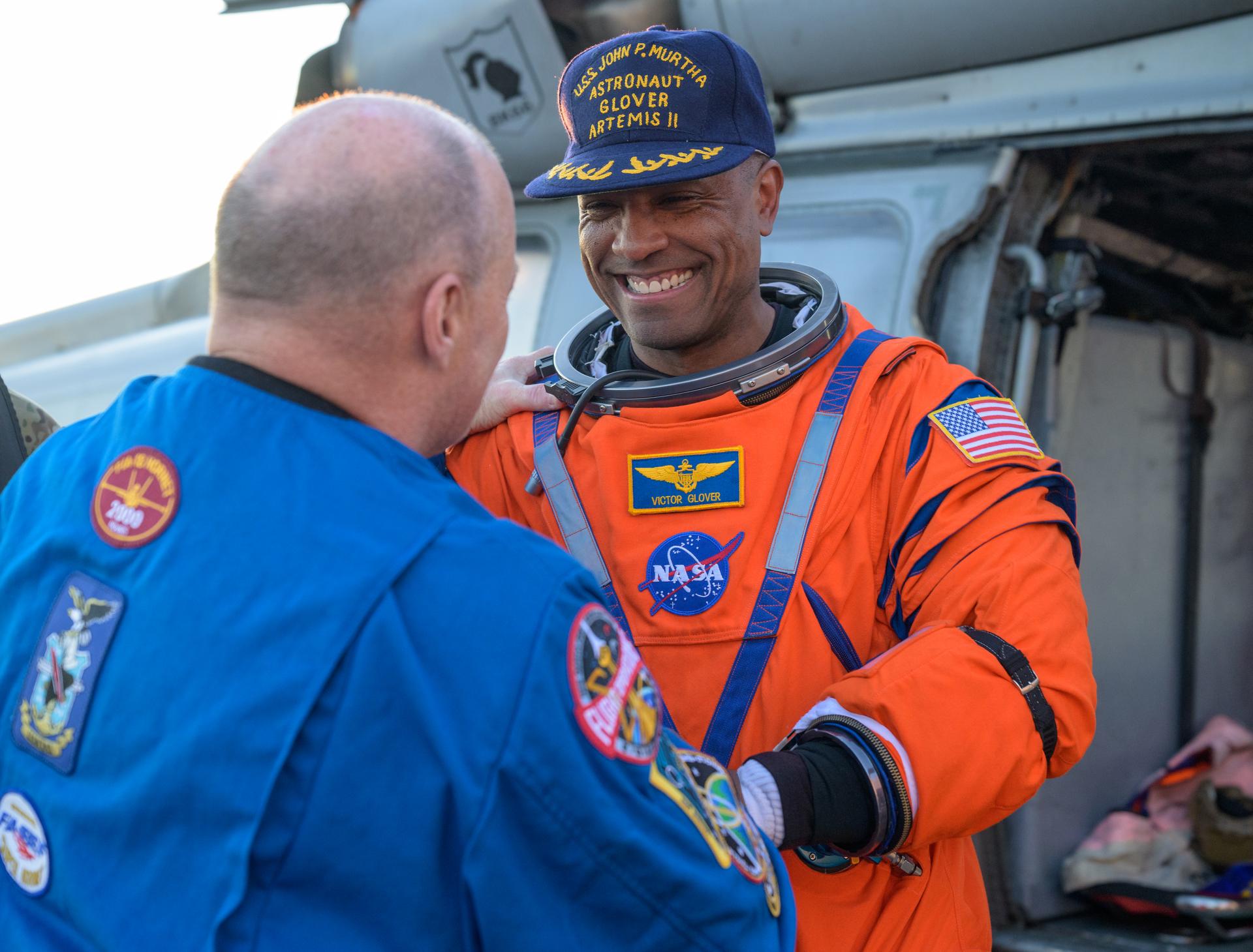 NASA astronaut Victor Glover, Artemis II pilot shakes hands with Scott Tingle, Chief of the Astronaut Office as he is assisted from a Navy MH-60 Seahawk from Helicopter Sea Combat Squadron (HSC) 23 on the flight deck of USS John P. Murtha after he and fellow crewmates NASA Astronauts Reid Wiseman,  Christina Koch, and CSA (Canadian Space Agency) astronaut Jeremy Hansen, Artemis II mission specialist were extracted from their Orion spacecraft after splashdown, Friday, April 10, 2026, in the Pacific Ocean off the coast of California. NASA’s Artemis II mission took the quartet on a nearly 10-day journey around the Moon and back to Earth. Following a splashdown at 5:07 p.m. PDT (8:07 p.m. EDT), NASA, U.S. Navy, and U.S. Air Force teams are working to bring the Orion spacecraft aboard the recovery ship. Photo Credit: (NASA/Bill Ingalls)