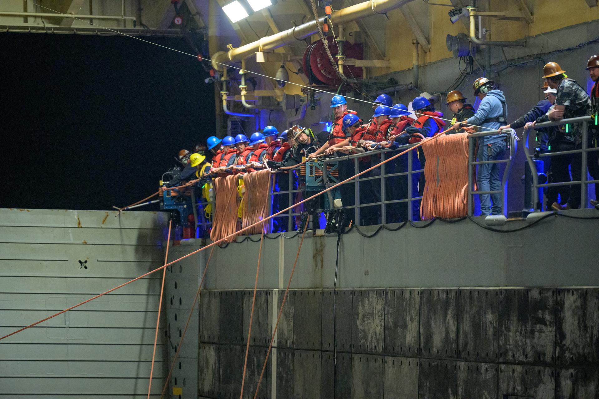 Teams prepare to recover NASA’s Orion spacecraft into the well deck of USS John P. Murtha in the Pacific Ocean off the coast of California, Friday, April 10, 2026. NASA’s Artemis II mission, which took NASA astronauts Reid Wiseman, commander; Victor Glover, pilot; Christina Koch, mission specialist; and CSA (Canadian Space Agency) astronaut Jeremy Hansen, mission specialist on a nearly 10-day journey around the Moon and back to Earth, splashed down at 5:07 p.m. PDT (8:07 p.m. EDT).  Photo Credit: (NASA/Bill Ingalls)