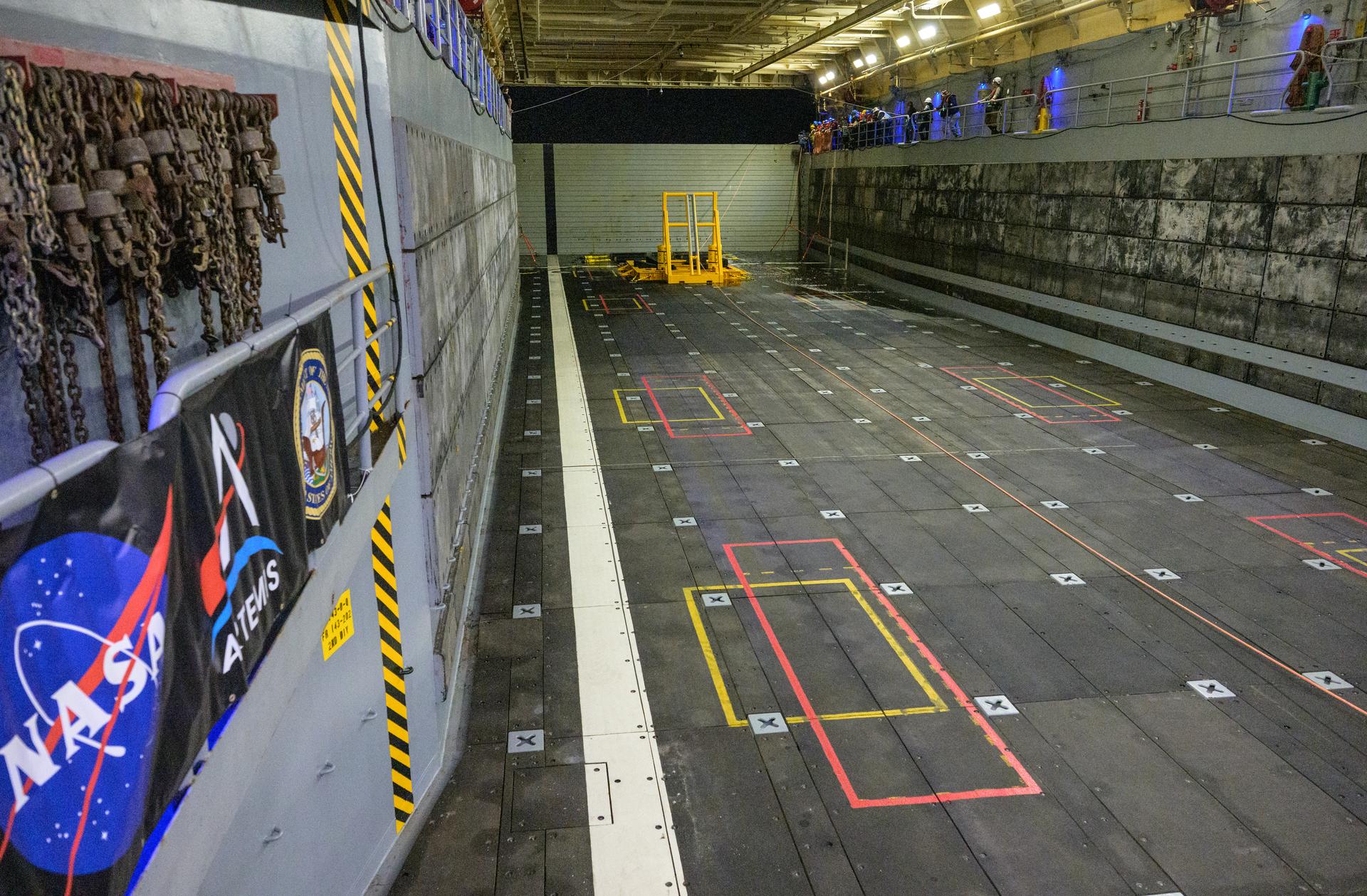 Teams prepare to recover NASA’s Orion spacecraft into the well deck of USS John P. Murtha in the Pacific Ocean off the coast of California, Friday, April 10, 2026. NASA’s Artemis II mission, which took NASA astronauts Reid Wiseman, commander; Victor Glover, pilot; Christina Koch, mission specialist; and CSA (Canadian Space Agency) astronaut Jeremy Hansen, mission specialist on a nearly 10-day journey around the Moon and back to Earth, splashed down at 5:07 p.m. PDT (8:07 p.m. EDT).  Photo Credit: (NASA/Bill Ingalls)
