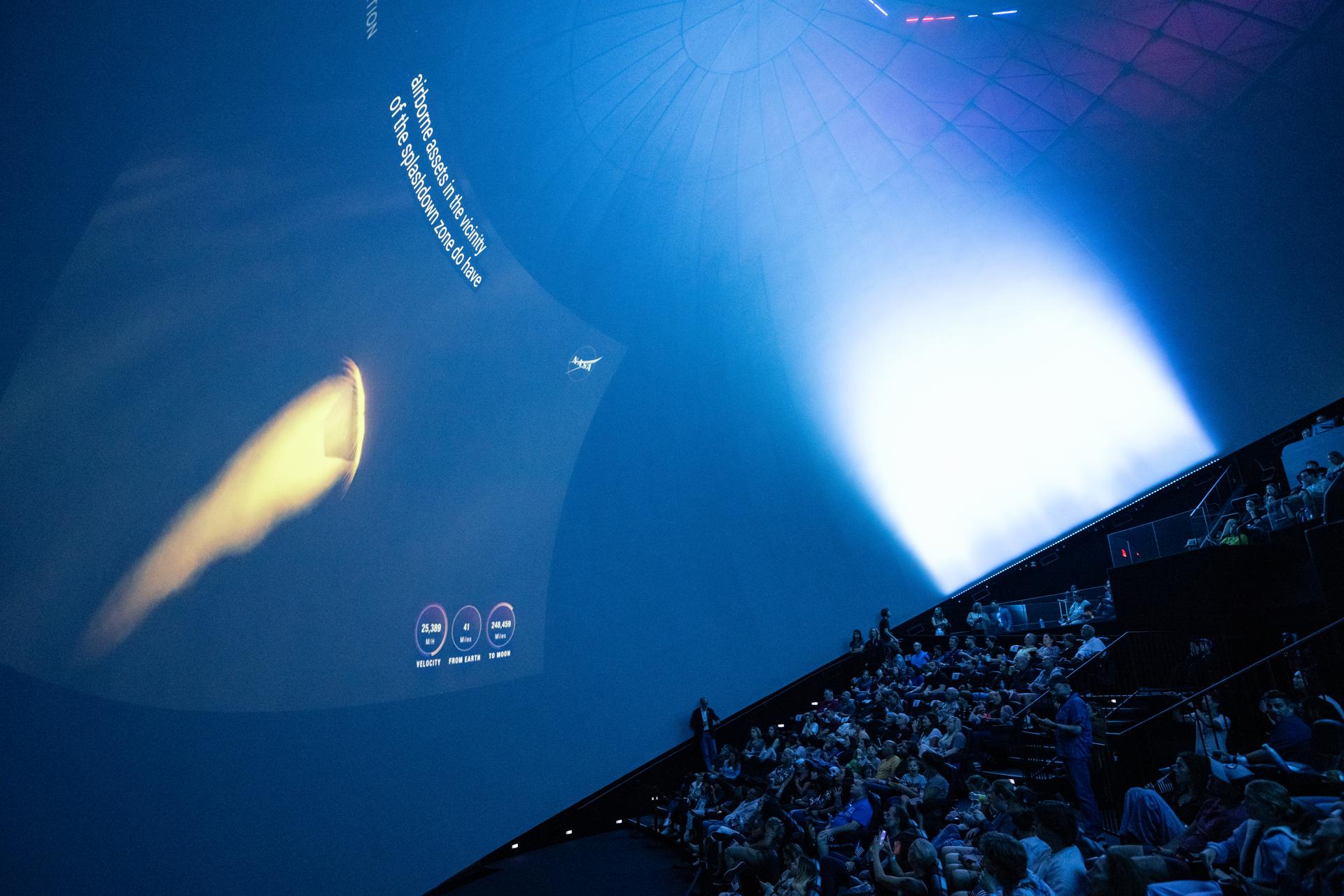 Guests at the Fleet Science Center in San Diego, California watch the live broadcast of NASA’s Orion spacecraft with Artemis II crew members NASA astronauts Reid Wiseman, commander; Victor Glover, pilot; Christina Koch, mission specialist; and CSA (Canadian Space Agency) astronaut Jeremy Hansen, mission specialist aboard landing in the Pacific Ocean off the coast of California, Friday, April 10, 2026. NASA’s Artemis II mission took Wiseman, Glover, Koch, and Hansen on a 10-day journey around the Moon and back to Earth. Photo Credit: (NASA/Keegan Barber)