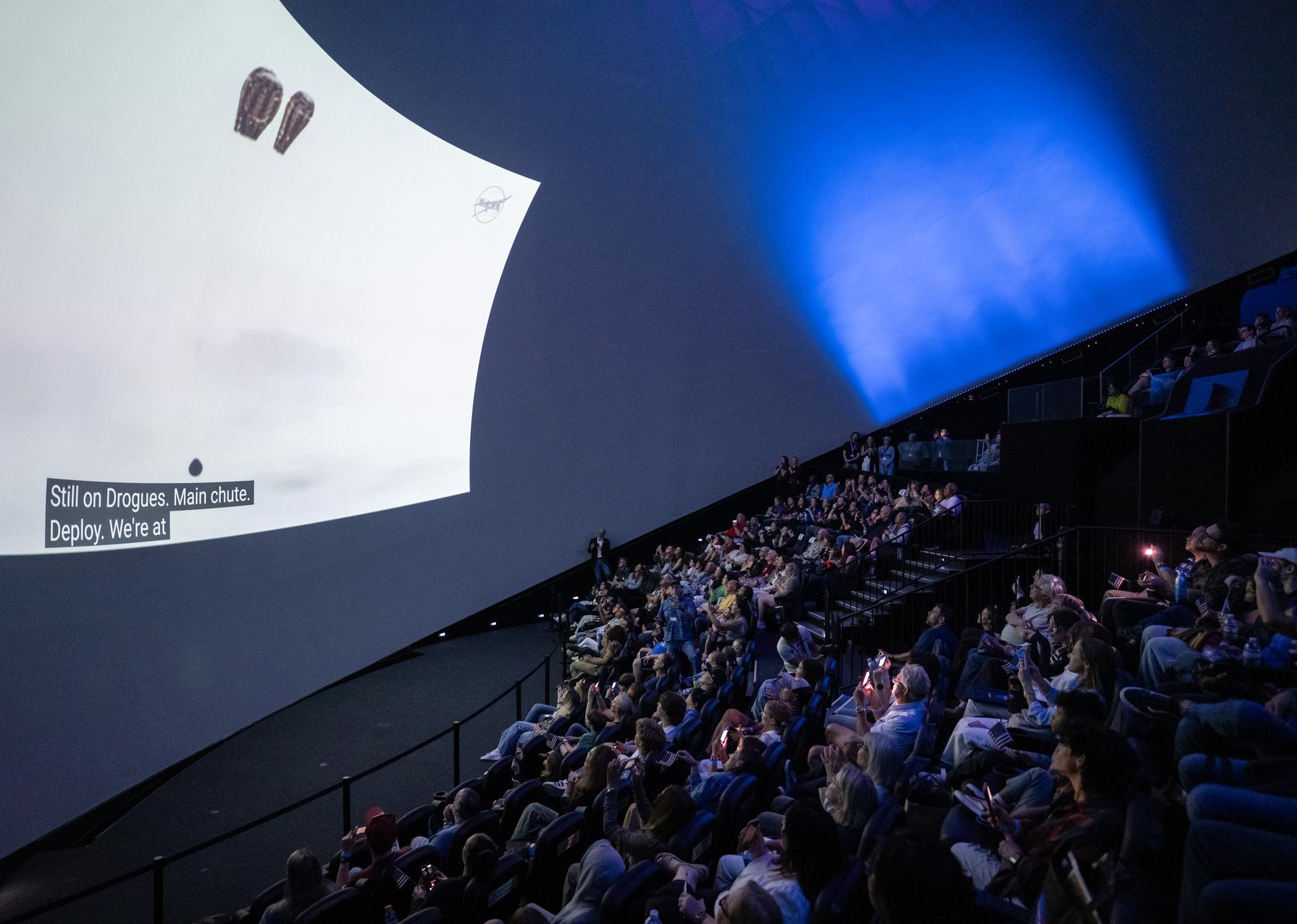Guests at the Fleet Science Center in San Diego, California watch the live broadcast of NASA’s Orion spacecraft with Artemis II crew members NASA astronauts Reid Wiseman, commander; Victor Glover, pilot; Christina Koch, mission specialist; and CSA (Canadian Space Agency) astronaut Jeremy Hansen, mission specialist aboard landing in the Pacific Ocean off the coast of California, Friday, April 10, 2026. NASA’s Artemis II mission took Wiseman, Glover, Koch, and Hansen on a 10-day journey around the Moon and back to Earth. Photo Credit: (NASA/Keegan Barber)