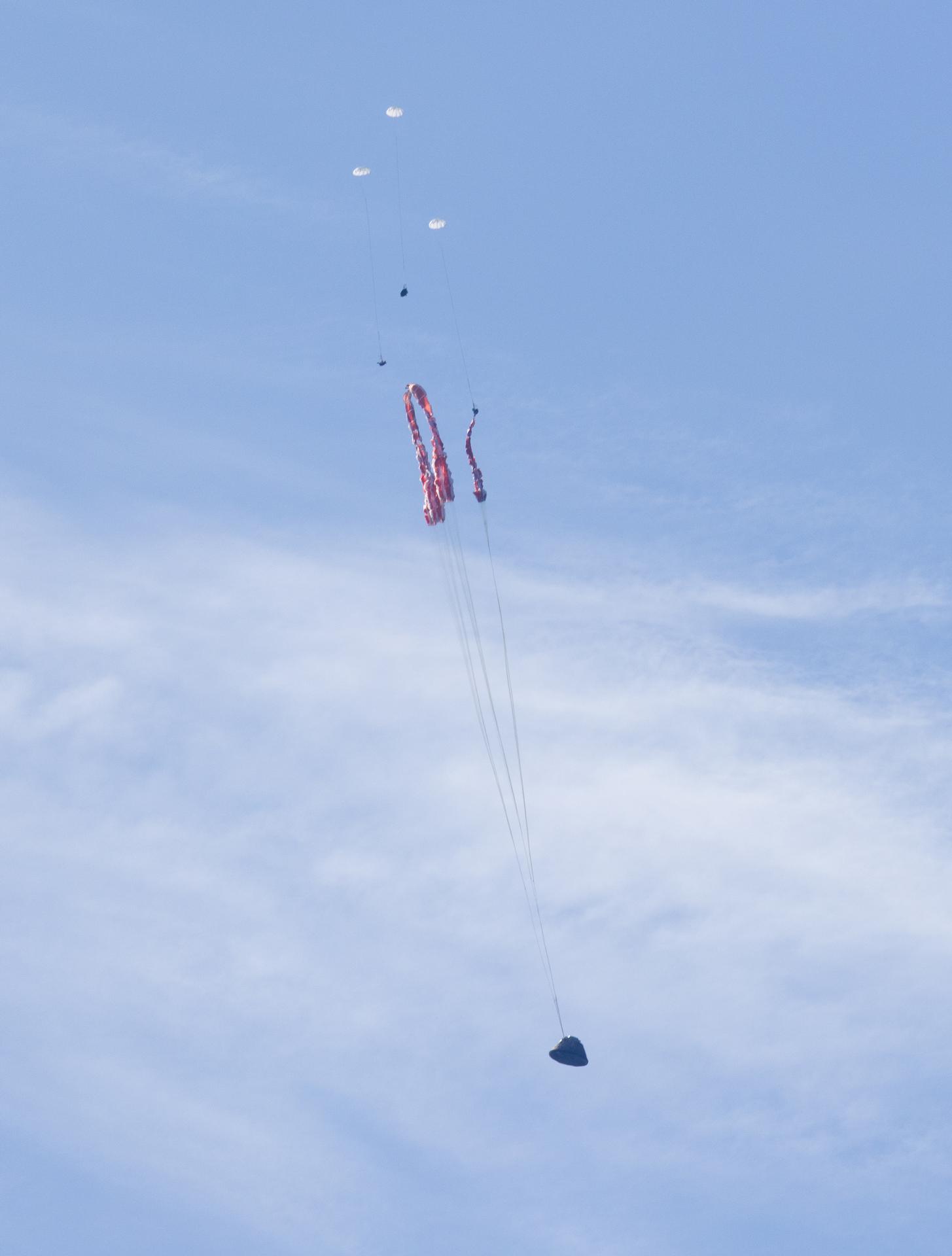 NASA’s Orion spacecraft with Artemis II crewmembers NASA astronauts Reid Wiseman, commander; Victor Glover, pilot; Christina Koch, mission specialist; and CSA (Canadian Space Agency) astronaut Jeremy Hansen, mission specialist aboard is seen as the main parachutes begin to deploy as it lands in the Pacific Ocean off the coast of California, Friday, April 10, 2026. NASA’s Artemis II mission took Wiseman, Glover, Koch, and Hansen on a nearly 10-day journey around the Moon and back to Earth. Following a splashdown at 5:07 p.m. PDT (8:07 p.m. EDT), NASA, U.S. Navy, and U.S. Air Force teams are working to bring the crewmembers and Orion spacecraft aboard USS John P. Murtha.  Photo Credit: (NASA/Joel Kowsky)