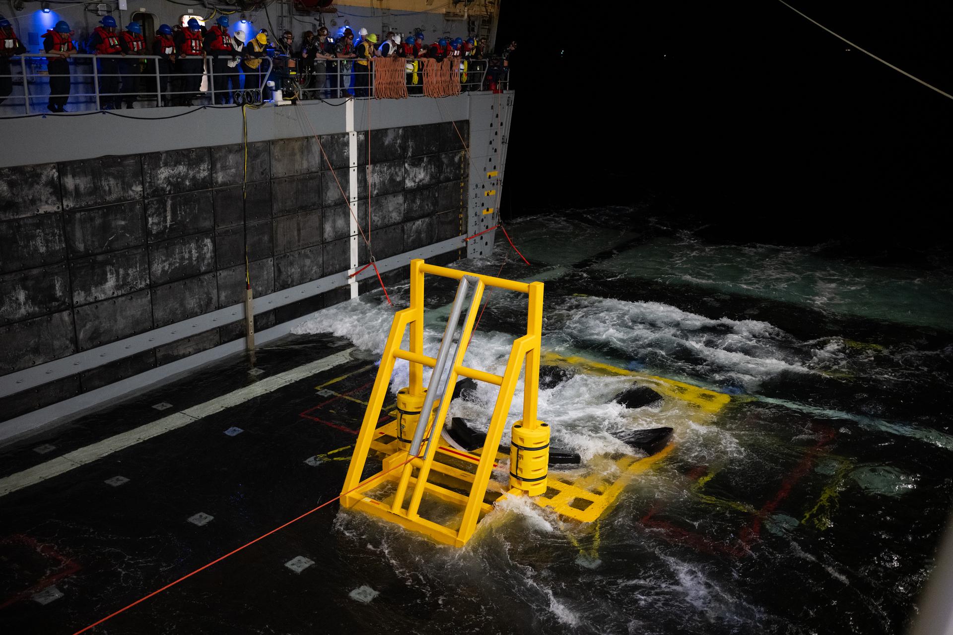 NASA’s Orion spacecraft is seen as the agency’s Landing and Recovery team, along with U.S. Navy personnel are seen as they prepare to recover the spacecraft into the well deck of USS John P. Murtha in the Pacific Ocean off the coast of California, Friday, April 10, 2026. NASA’s Artemis II mission, which took NASA astronauts Reid Wiseman, commander; Victor Glover, pilot; Christina Koch, mission specialist; and CSA (Canadian Space Agency) astronaut Jeremy Hansen, mission specialist on a nearly 10-day journey around the Moon and back to Earth, splashed down at 5:07 p.m. PDT (8:07 p.m. EDT).  Photo Credit: (NASA/Joel Kowsky)
