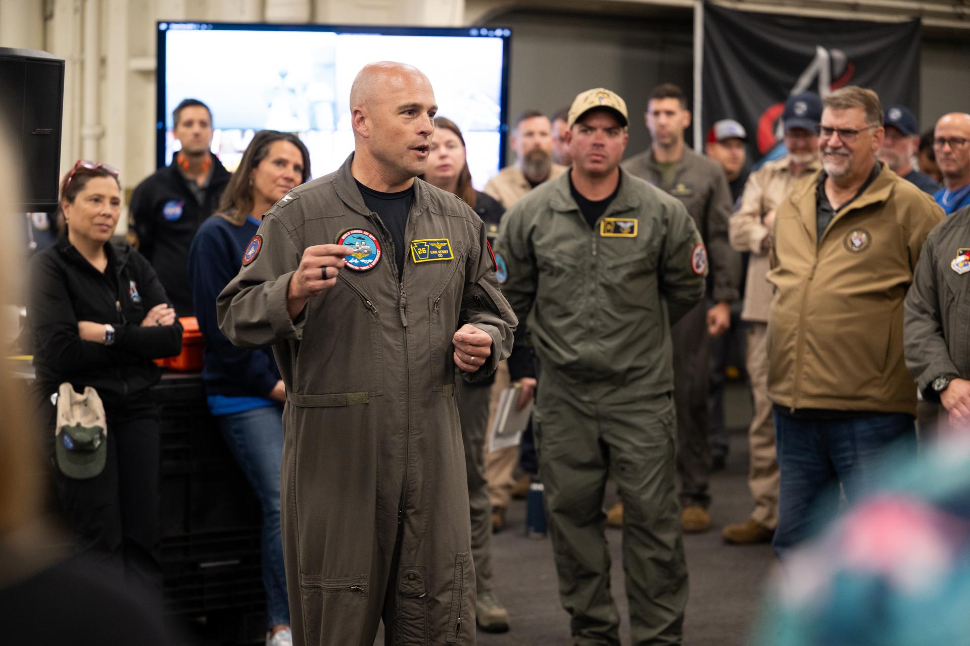Capt. Erik Kenny, commanding officer, USS John P. Murtha (LPD 26) speaks to NASA and U.S. military recovery team members onboard USS John P. Murtha as they prepare for the return of NASA’s Orion spacecraft with Artemis II crewmembers NASA astronauts Reid Wiseman, commander; Victor Glover, pilot; Christina Koch, mission specialist; and CSA (Canadian Space Agency) astronaut Jeremy Hansen, mission specialist aboard in the Pacific Ocean off the coast of California, Friday, April 10, 2026. NASA’s Artemis II mission took Wiseman, Glover, Koch, and Hansen on a nearly 10-day journey around the Moon and back to Earth. The quartet splashed down in the Pacific Ocean at 5:07 p.m. PDT (8:07 p.m. EDT). Photo Credit: (NASA/Joel Kowsky)