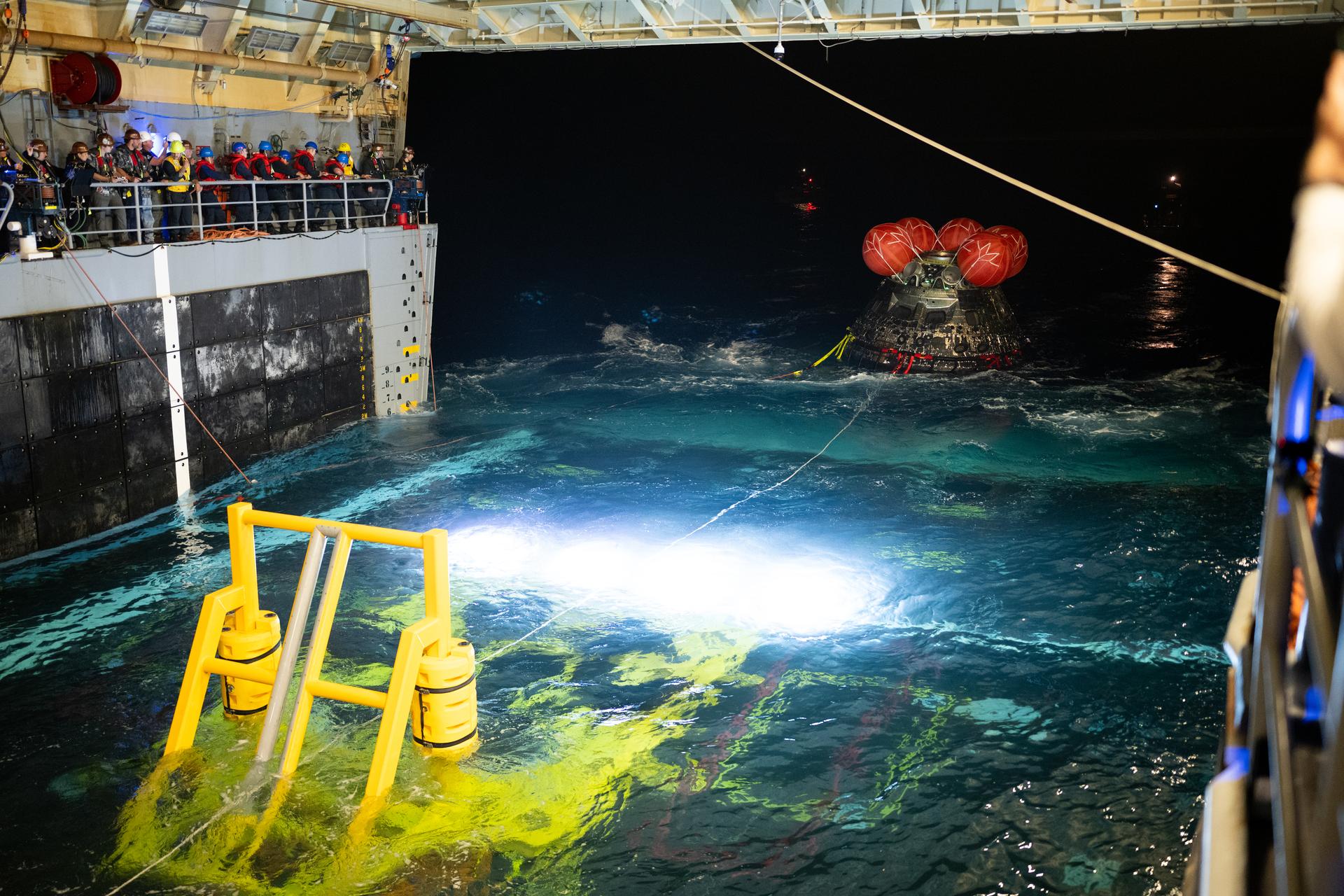 NASA’s Orion spacecraft is seen as the agency’s Landing and Recovery team, along with U.S. Navy personnel work to recover the spacecraft into the well deck of USS John P. Murtha in the Pacific Ocean off the coast of California, Saturday, April 11, 2026. NASA’s Artemis II mission, which took NASA astronauts Reid Wiseman, commander; Victor Glover, pilot; Christina Koch, mission specialist; and CSA (Canadian Space Agency) astronaut Jeremy Hansen, mission specialist on a nearly 10-day journey around the Moon and back to Earth, splashed down at 5:07 p.m. PDT (8:07 p.m. EDT).  Photo Credit: (NASA/Joel Kowsky)