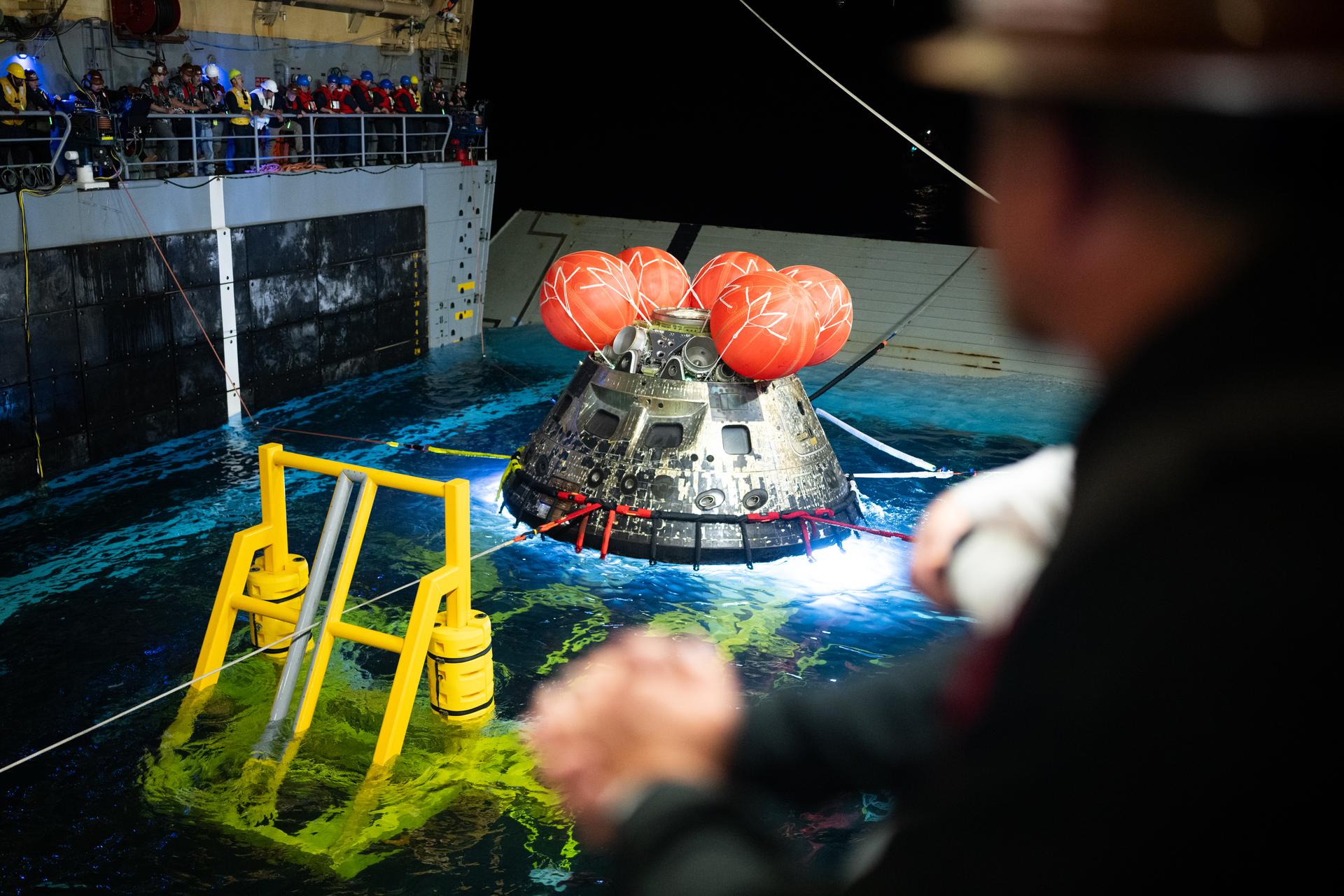 NASA’s Orion spacecraft is seen as the agency’s Landing and Recovery team, along with U.S. Navy personnel work to recover the spacecraft into the well deck of USS John P. Murtha in the Pacific Ocean off the coast of California, Saturday, April 11, 2026. NASA’s Artemis II mission, which took NASA astronauts Reid Wiseman, commander; Victor Glover, pilot; Christina Koch, mission specialist; and CSA (Canadian Space Agency) astronaut Jeremy Hansen, mission specialist on a nearly 10-day journey around the Moon and back to Earth, splashed down at 5:07 p.m. PDT (8:07 p.m. EDT).  Photo Credit: (NASA/Joel Kowsky)