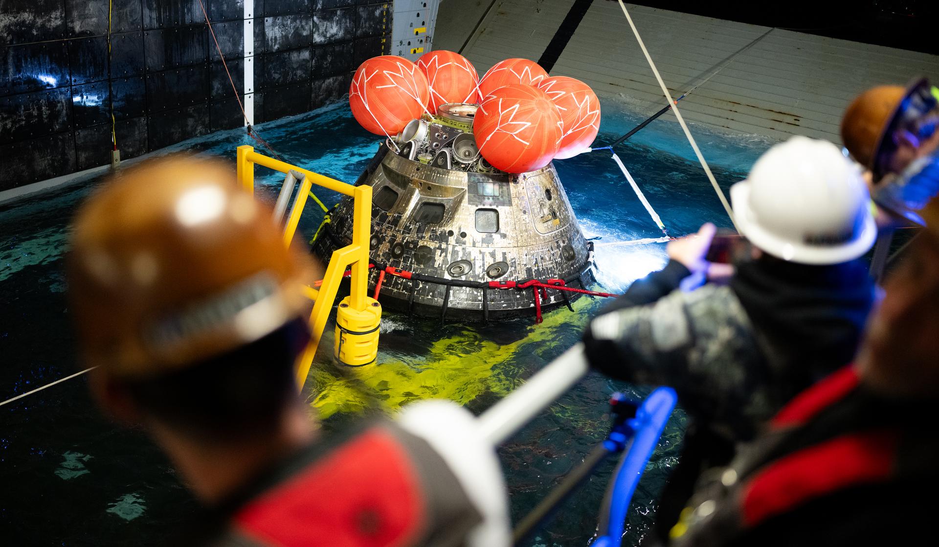 NASA’s Orion spacecraft is seen as the agency’s Landing and Recovery team, along with U.S. Navy personnel work to recover the spacecraft into the well deck of USS John P. Murtha in the Pacific Ocean off the coast of California, Saturday, April 11, 2026. NASA’s Artemis II mission, which took NASA astronauts Reid Wiseman, commander; Victor Glover, pilot; Christina Koch, mission specialist; and CSA (Canadian Space Agency) astronaut Jeremy Hansen, mission specialist on a nearly 10-day journey around the Moon and back to Earth, splashed down at 5:07 p.m. PDT (8:07 p.m. EDT).  Photo Credit: (NASA/Joel Kowsky)