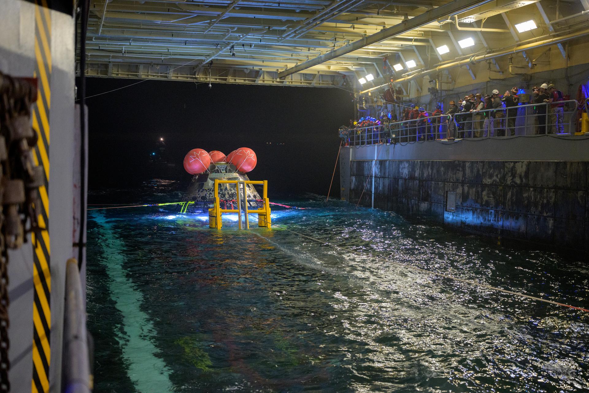 NASA’s Orion spacecraft is seen as the agency’s Landing and Recovery team, along with U.S. Navy personnel work to recover the spacecraft into the well deck of USS John P. Murtha in the Pacific Ocean off the coast of California, Saturday, April 11, 2026. NASA’s Artemis II mission, which took NASA astronauts Reid Wiseman, commander; Victor Glover, pilot; Christina Koch, mission specialist; and CSA (Canadian Space Agency) astronaut Jeremy Hansen, mission specialist on a 10-day journey around the Moon and back to Earth, splashed down at at 5:07 p.m. PDT (8:07 p.m. EDT).  Photo Credit: (NASA/Bill Ingalls)