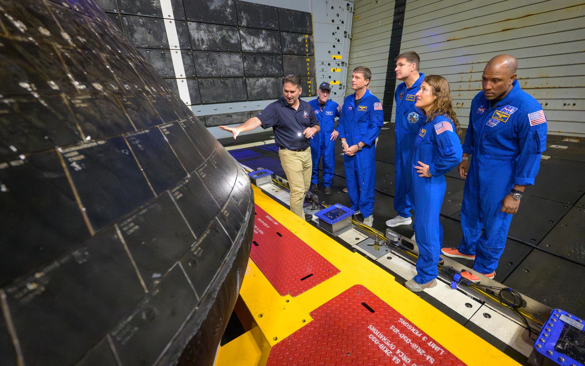 NASA Orion Vehicle Integration Manager Luis Saucedo, left, inspects the Orion spacecraft with NASA Flight Surgeon Richard Scheuring, NASA astronaut Reid Wiseman, commander; CSA (Canadian Space Agency) astronaut Jeremy Hansen, mission specialist; Christina Koch, mission specialist; and NASA astronaut Victor Glover, Artemis II pilot, right, in the well deck of USS John P. Murtha, Saturday, April 11, 2026, in the Pacific Ocean off the coast of California. The quartet splashed down in the Pacific Ocean, Friday, April 10 at 5:07 p.m. PDT (8:07p.m. EDT). Photo Credit: (NASA/Bill Ingalls)