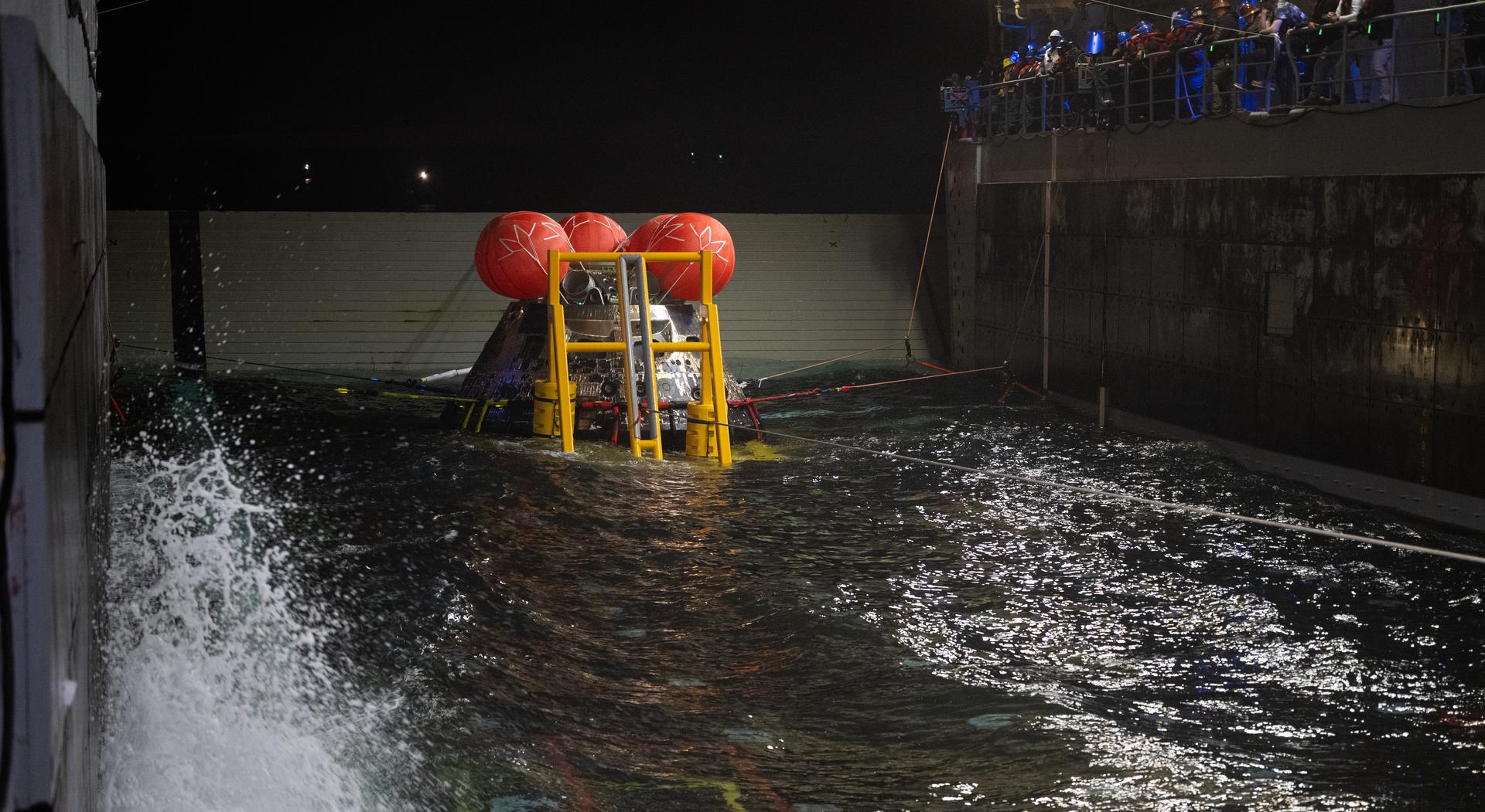NASA’s Orion spacecraft is seen as the agency’s Landing and Recovery team, along with U.S. Navy personnel work to recover the spacecraft into the well deck of USS John P. Murtha in the Pacific Ocean off the coast of California, Saturday, April 11, 2026. NASA’s Artemis II mission, which took NASA astronauts Reid Wiseman, commander; Victor Glover, pilot; Christina Koch, mission specialist; and CSA (Canadian Space Agency) astronaut Jeremy Hansen, mission specialist on a nearly 10-day journey around the Moon and back to Earth, splashed down at 5:07 p.m. PDT (8:07 p.m. EDT).  Photo Credit: (NASA/Joel Kowsky)