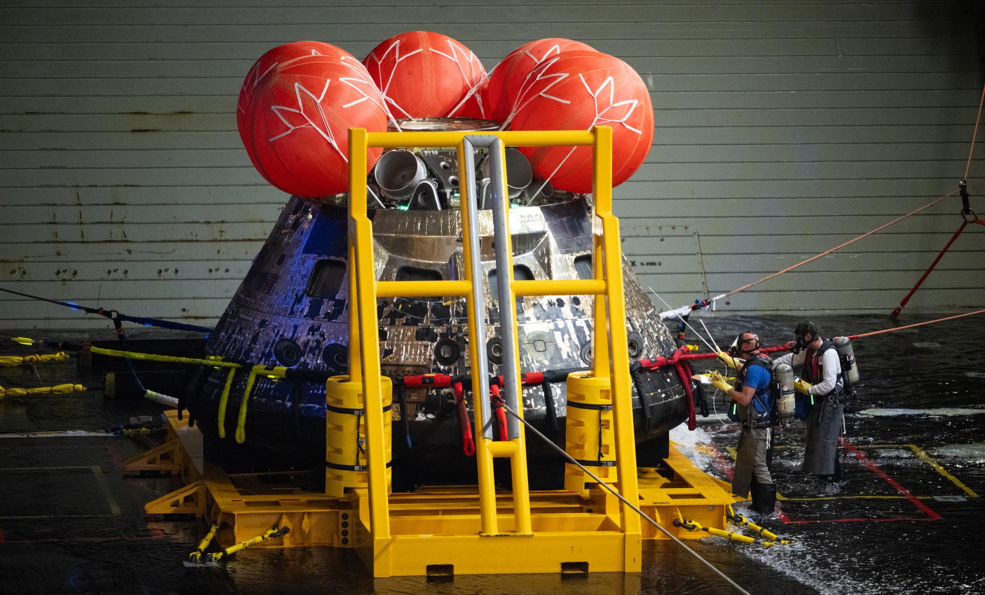 NASA’s Orion spacecraft is seen as members of agency’s Landing and Recovery team perform hazard checks after recovering the spacecraft...