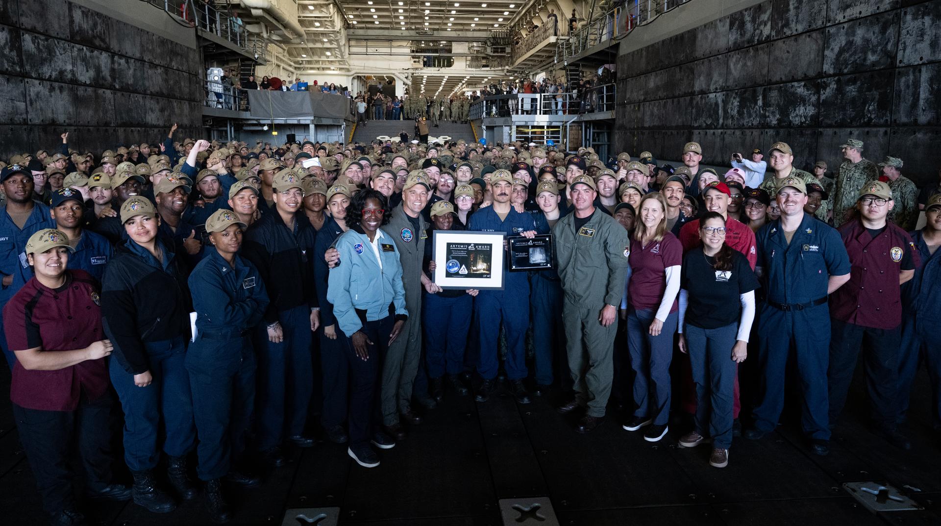 The crew of USS John P. Murtha takes a group picture with Lakiesha Hawkins, acting deputy associate administrator for NASA's Exploration Systems Development Mission Directorate, Janet Petro, director of NASA's Kennedy Space Center, and Lilian Villarreal, Artemis II landing and recovery director for Exploration Ground Systems at NASA's Kennedy Space Center in the well deck of John P. Murtha, Saturday, April 11, 2026, at Naval Base San Diego after supporting recovery operations for NASA’s Artemis II mission. The agency’s Artemis II mission, which took NASA astronauts Reid Wiseman, commander; Victor Glover, pilot; Christina Koch, mission specialist; and CSA (Canadian Space Agency) astronaut Jeremy Hansen, mission specialist on a nearly 10-day journey around the Moon and back to Earth, splashed down at 5:07 p.m. PDT (8:07 p.m. EDT) on April 10 in the Pacific Ocean off the coast of California.  Photo Credit: (NASA/Joel Kowsky)