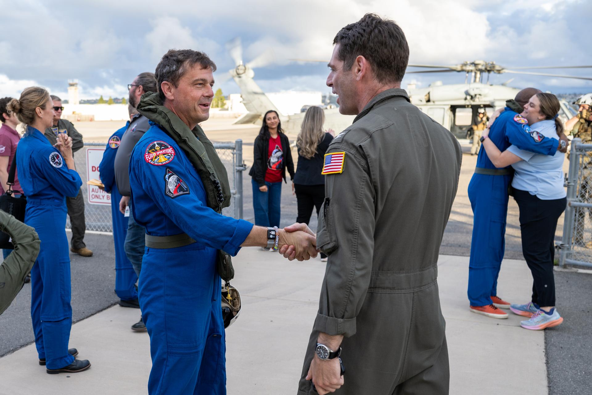 Artemis II NASA astronaut Reid Wiseman, commander, greets Capt. Loren “Wookie” Jacobi of Naval Base San Diego after being flown from USS John P. Murtha to Naval Air Station North Island on Navy MH-60 Seahawks from Helicopter Sea Combat Squadron (HSC) 23, Saturday, April 11, 2026, following a splashdown in the Pacific Ocean off the coast of California at 5:07 p.m. PDT (8:07 p.m. EDT) on April 10. NASA’s Artemis II mission took NASA astronauts Reid Wiseman, commander; Victor Glover, pilot; Christina Koch, mission specialist; and CSA (Canadian Space Agency) astronaut Jeremy Hansen, mission specialist on a nearly ten day journey around the Moon and back to Earth. Photo Credit: (NASA/Keegan Barber)