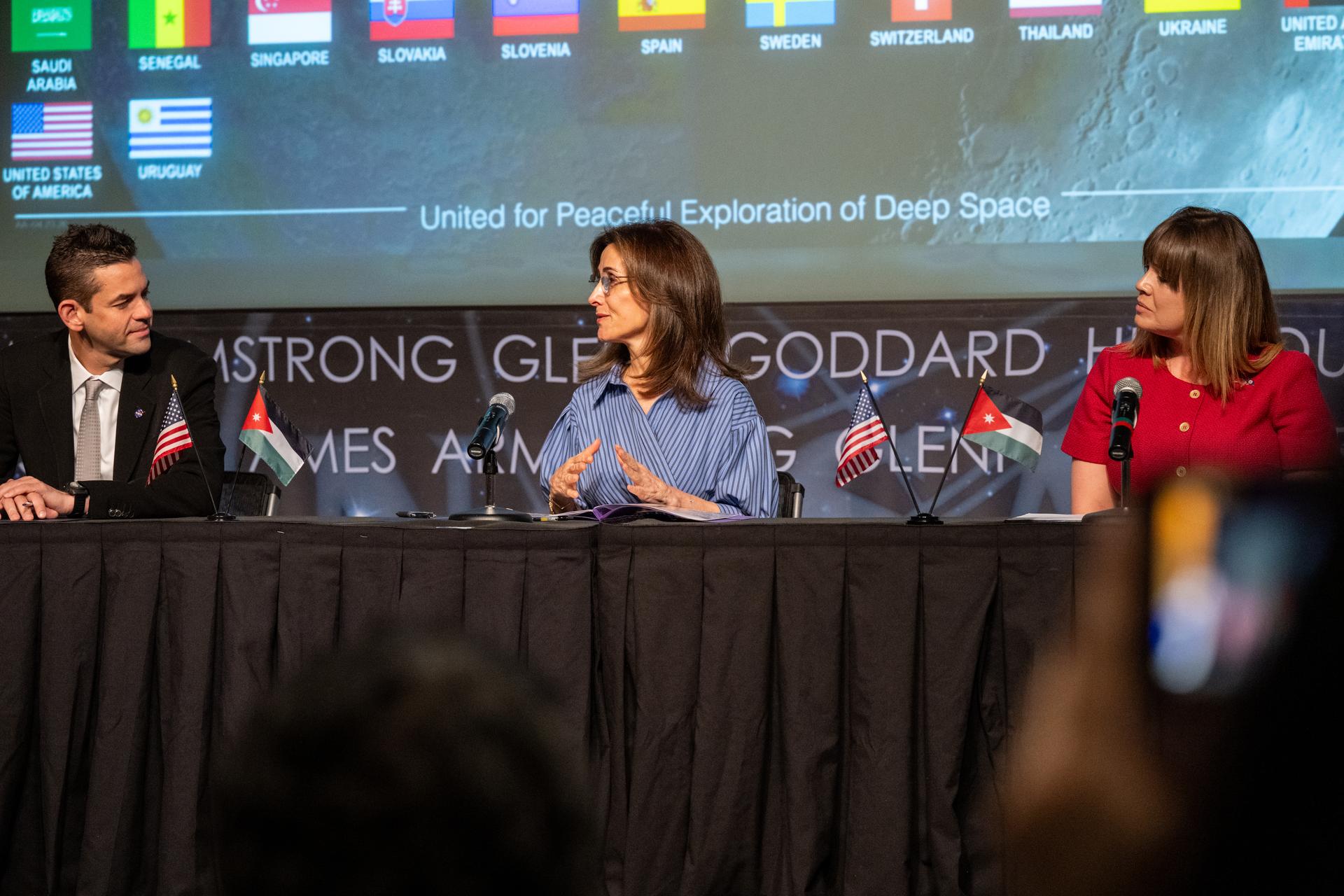 Ambassador of Jordan to the United States Dina Kawar, center, delivers remarks during an Artemis Accords signing ceremony alongside NASA Administrator Jared Isaacman, left, and Acting Principal Deputy Assistant Secretary of State for Oceans and International Environmental and Scientific Affairs Ruth Perry, right, Thursday, April 23, 2026, at the Mary W. Jackson NASA Headquarters building in Washington. The Hashemite Kingdom of Jordan is the 63rd country to sign the Artemis Accords, which establish a practical set of principles to guide space exploration cooperation among nations participating in NASA’s Artemis program. Photo Credit: (NASA/Keegan Barber)