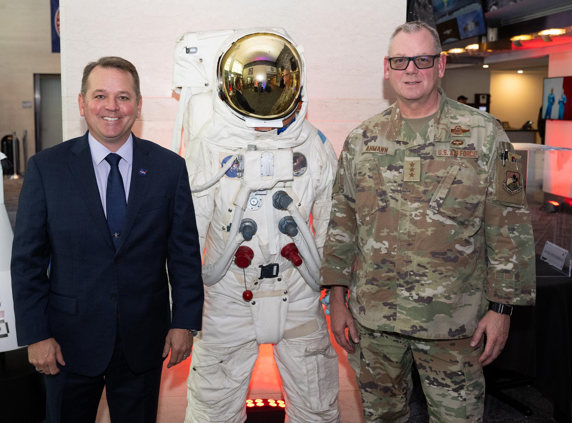 NASA Deputy Administrator Matt Anderson, left, and U.S. Air Force Lt. Gen. Luke Ahmann, Commander, Continental U.S. North American Aerospace Defense Command Region; Commander, 1st Air Force, pose for a picture with a replica A7L spacesuit,  Tuesday, June 30, 2026, at the Mary W. Jackson NASA Headquarters building in Washington.  Photo Credit: (NASA/Joel Kowsky)