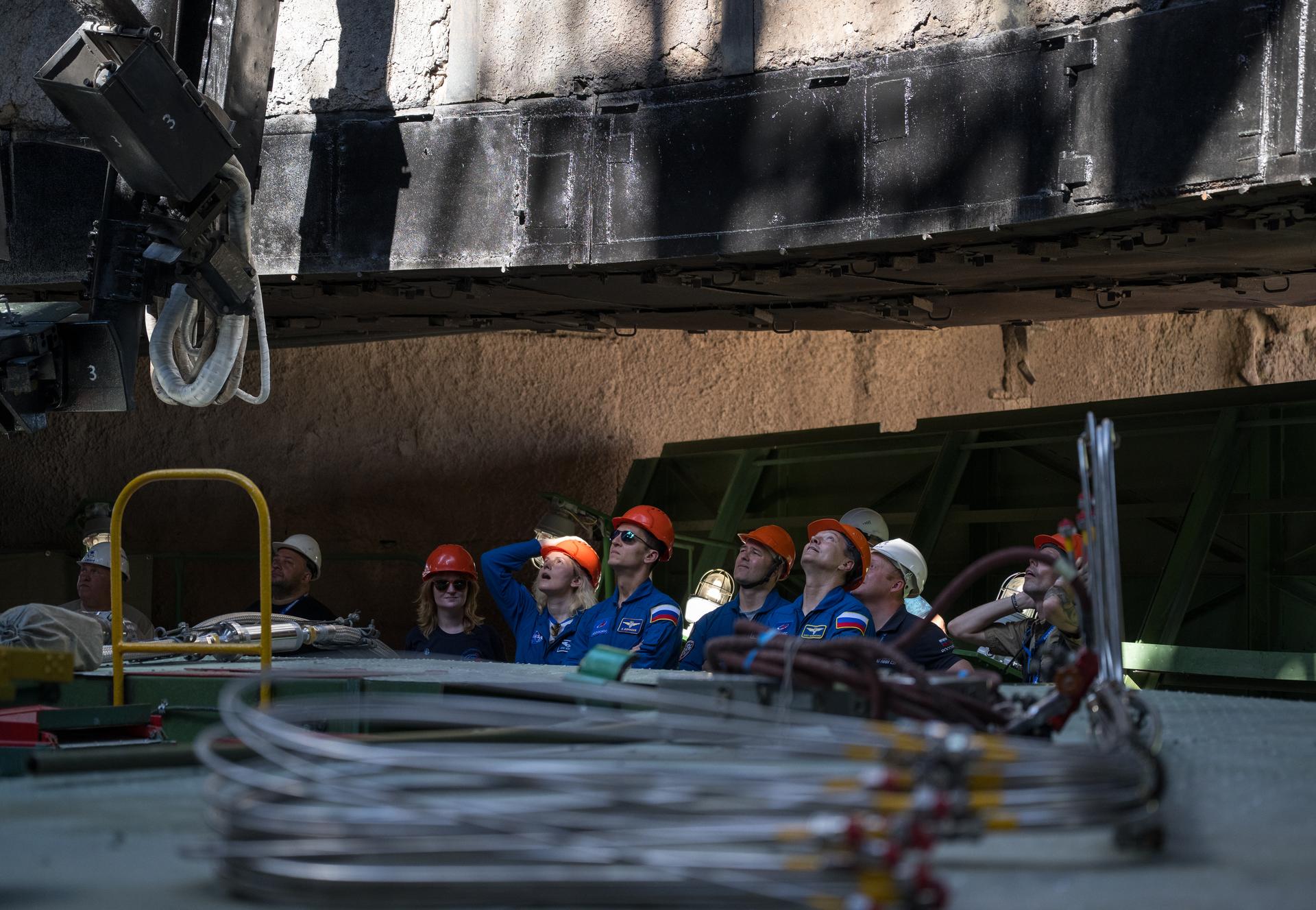 Expedition 75 backup crewmembers: NASA astronuaut Deniz Burnham, left, Roscosmos cosmonauts Konstantin Borisov, and Dmitry Petelin, along with Head of Gargarin Cosmonaut Training Center Oleg Kononenko, right, watch from the flame trench as the Soyuz rocket is raised into position at the Site 31 launch pad of the Baikonur Cosmodrome in Kazakhstan, Saturday, July 11, 2026. Expedition 75 crewmembers: NASA astronaut Anil Menon, Roscosmos cosmonauts Pyotr Dubrov and Anna Kikina are scheduled to launch aboard their Soyuz MS-29 spacecraft on July 14. Photo Credit: (NASA/Bill Ingalls)