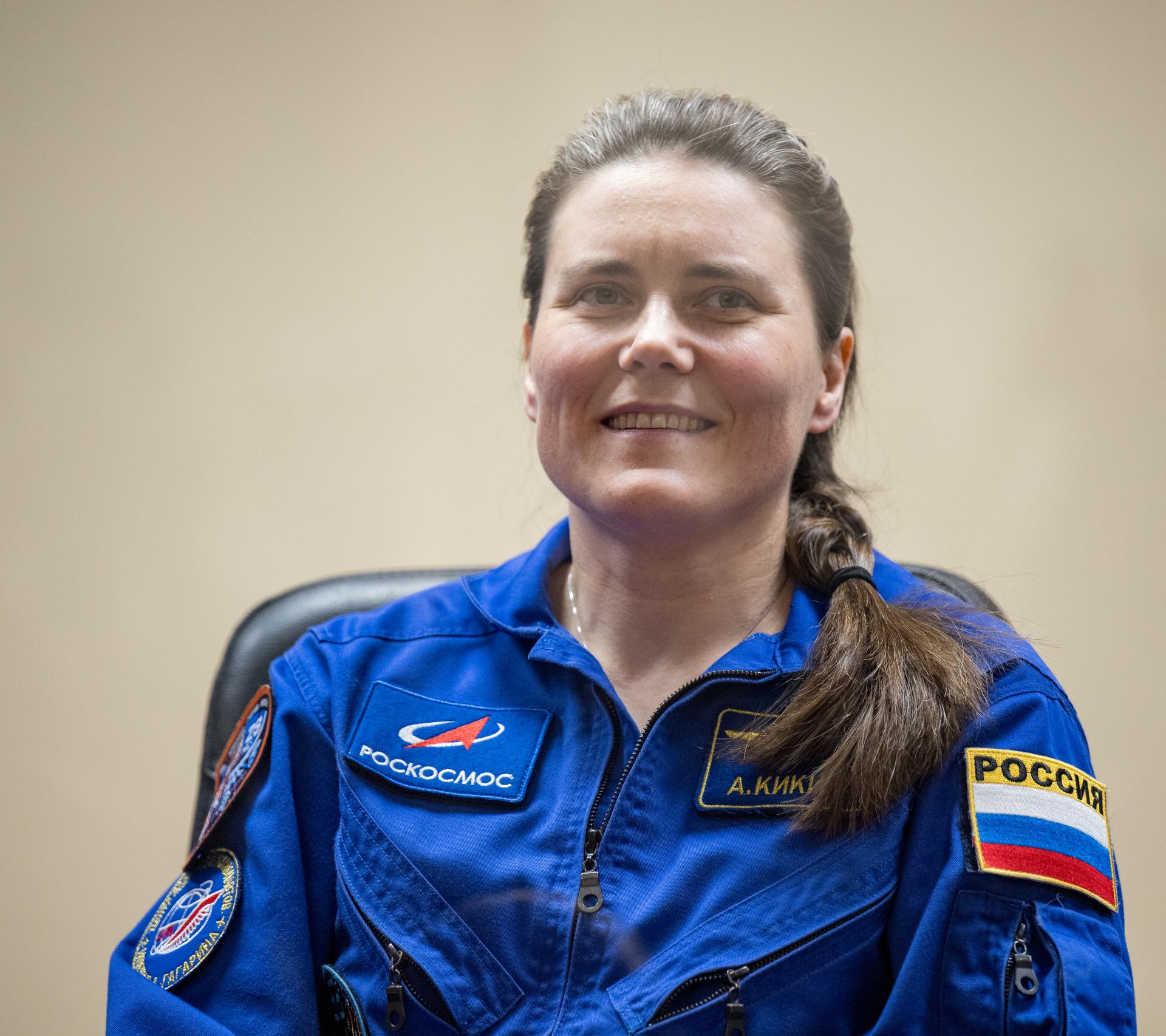 Roscosmos cosmonaut Anna Kikina is seen in quarantine, behind glass, during a press conference, Monday, July 13, 2026 a the Cosmonaut Hotel in Baikonur, Kazakhstan. Expedition 75 crewmembers: NASA astronaut Anil Menon, Roscosmos cosmonauts Pyotr Dubrov and Anna Kikina are scheduled to launch aboard the Soyuz MS-29 spacecraft to the International Space Station on July 14. Photo Credit: (NASA/Bill Ingalls)
