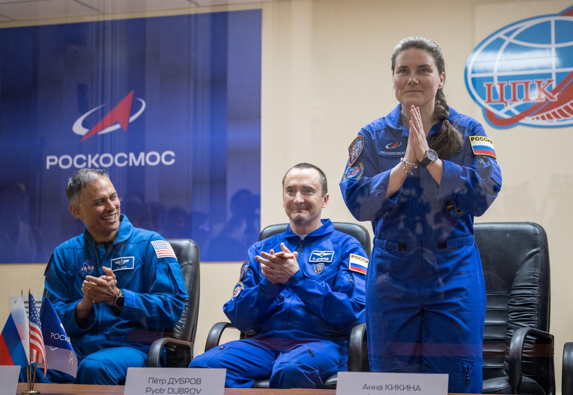 Expedition 75 crewmembers: NASA astronaut Anil Menon, left, Roscosmos cosmonauts Pyotr Dubrov and Anna Kikina, right, are seen in quarantine, behind glass, during a press conference, Monday, July 13, 2026 a the Cosmonaut Hotel in Baikonur, Kazakhstan. Menon, Dubrov, and Kikina are scheduled to launch aboard the Soyuz MS-29 spacecraft to the International Space Station on July 14. Photo Credit: (NASA/Bill Ingalls)