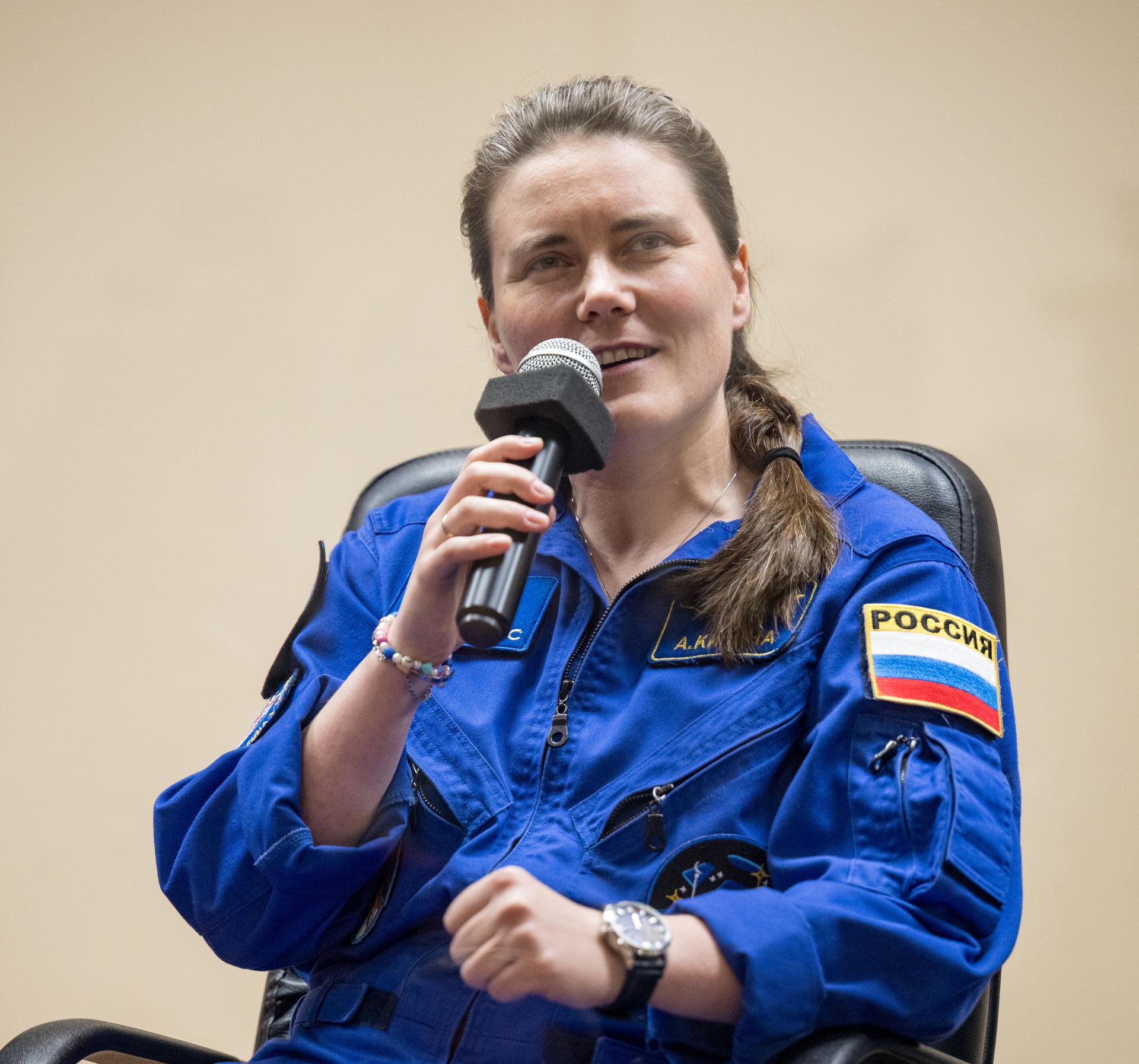Roscosmos cosmonaut Anna Kikina is seen in quarantine, behind glass, during a press conference, Monday, July 13, 2026 a the Cosmonaut Hotel in Baikonur, Kazakhstan. Expedition 75 crewmembers: NASA astronaut Anil Menon, Roscosmos cosmonauts Pyotr Dubrov and Anna Kikina are scheduled to launch aboard the Soyuz MS-29 spacecraft to the International Space Station on July 14. Photo Credit: (NASA/Bill Ingalls)