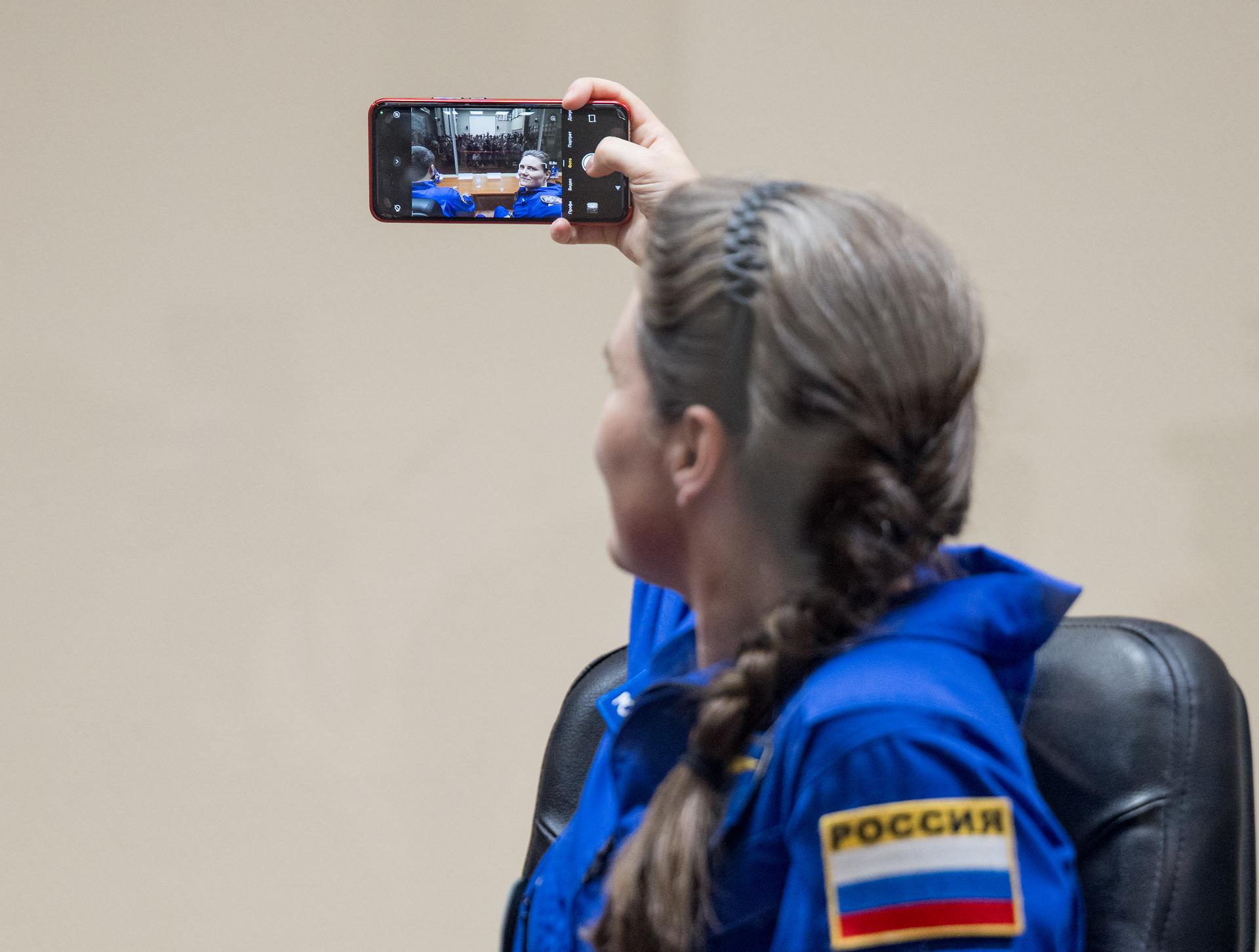 Roscosmos cosmonaut Anna Kikina is seen in quarantine, behind glass, during a press conference, Monday, July 13, 2026 a the Cosmonaut Hotel in Baikonur, Kazakhstan. Expedition 75 crewmembers: NASA astronaut Anil Menon, Roscosmos cosmonauts Pyotr Dubrov and Anna Kikina are scheduled to launch aboard the Soyuz MS-29 spacecraft to the International Space Station on July 14. Photo Credit: (NASA/Bill Ingalls)