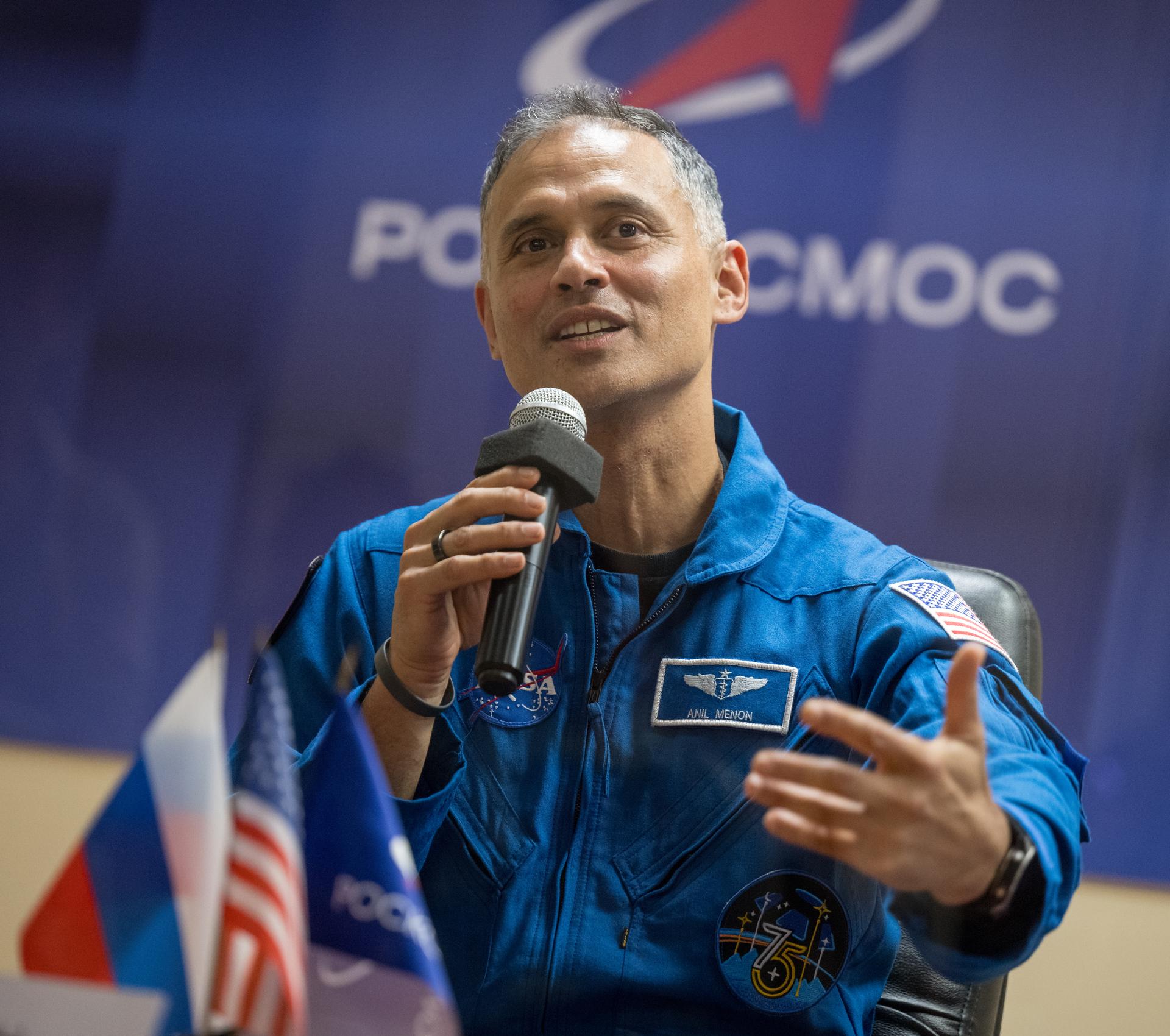 NASA astronaut Anil Menon is seen in quarantine, behind glass, during a press conference, Monday, July 13, 2026 a the Cosmonaut Hotel in Baikonur, Kazakhstan. Expedition 75 crewmembers: NASA astronaut Anil Menon, Roscosmos cosmonauts Pyotr Dubrov and Anna Kikina are scheduled to launch aboard the Soyuz MS-29 spacecraft to the International Space Station on July 14. Photo Credit: (NASA/Bill Ingalls)