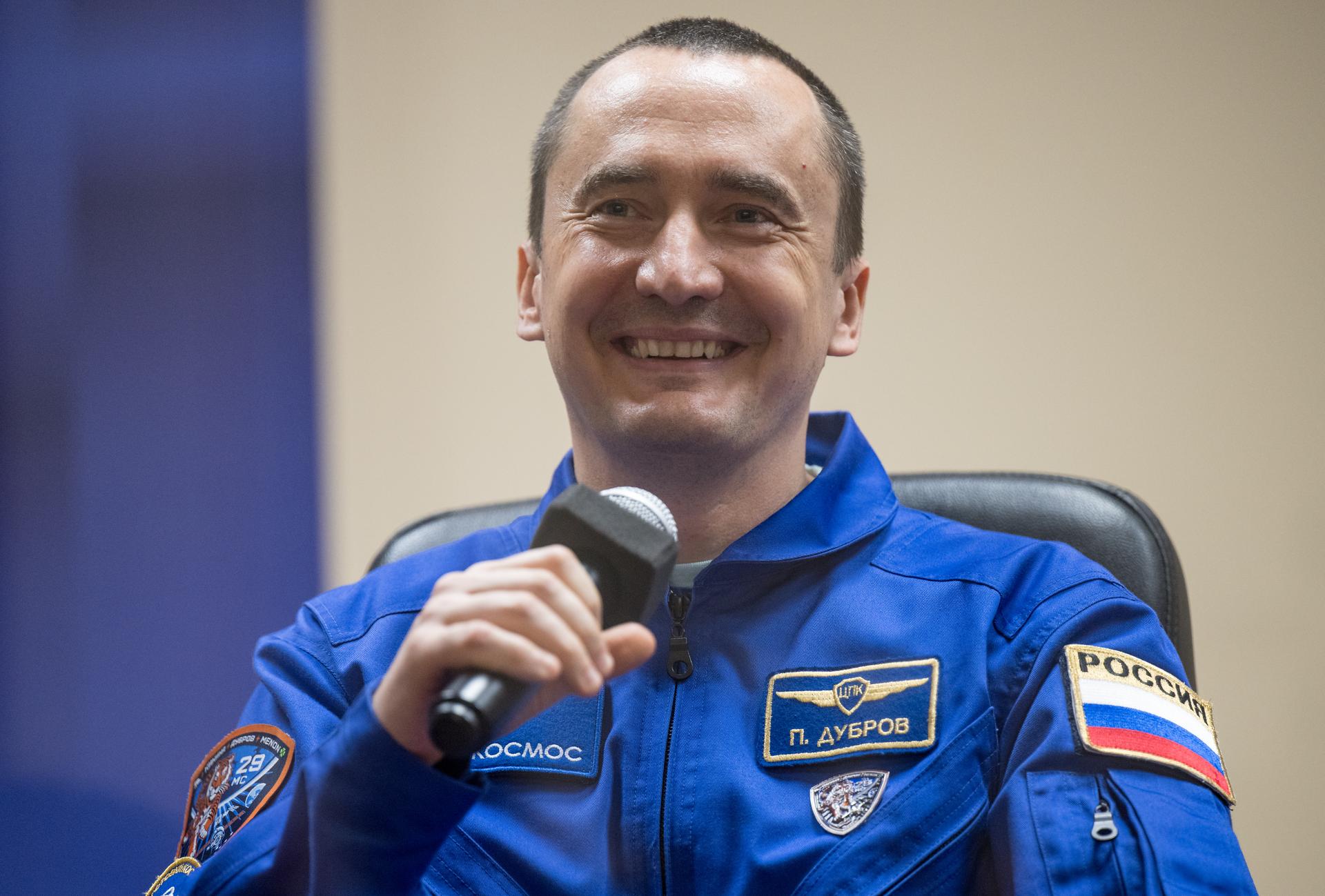 Roscosmos cosmonaut Pyotr Dubrov is seen in quarantine, behind glass, during a press conference, Monday, July 13, 2026 a the Cosmonaut Hotel in Baikonur, Kazakhstan. Expedition 75 crewmembers: NASA astronaut Anil Menon, Roscosmos cosmonauts Pyotr Dubrov and Anna Kikina are scheduled to launch aboard the Soyuz MS-29 spacecraft to the International Space Station on July 14. Photo Credit: (NASA/Bill Ingalls)