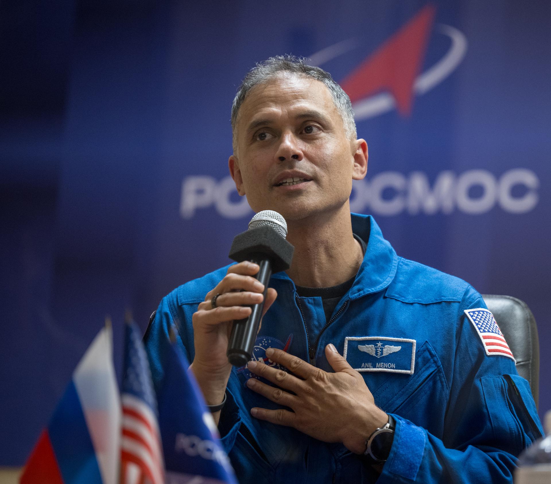 NASA astronaut Anil Menon is seen in quarantine, behind glass, during a press conference, Monday, July 13, 2026 a the Cosmonaut Hotel in Baikonur, Kazakhstan. Expedition 75 crewmembers: NASA astronaut Anil Menon, Roscosmos cosmonauts Pyotr Dubrov and Anna Kikina are scheduled to launch aboard the Soyuz MS-29 spacecraft to the International Space Station on July 14. Photo Credit: (NASA/Bill Ingalls)
