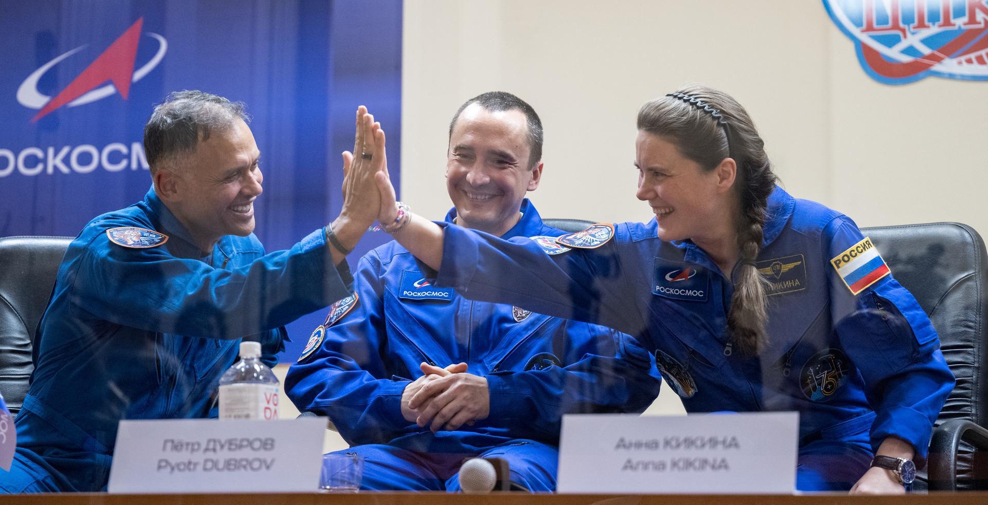 Expedition 75 crewmembers: NASA astronaut Anil Menon, left, Roscosmos cosmonauts Pyotr Dubrov and Anna Kikina, right, are seen in quarantine, behind glass, during a press conference, Monday, July 13, 2026 a the Cosmonaut Hotel in Baikonur, Kazakhstan. Menon, Dubrov, and Kikina are scheduled to launch aboard the Soyuz MS-29 spacecraft to the International Space Station on July 14. Photo Credit: (NASA/Bill Ingalls)