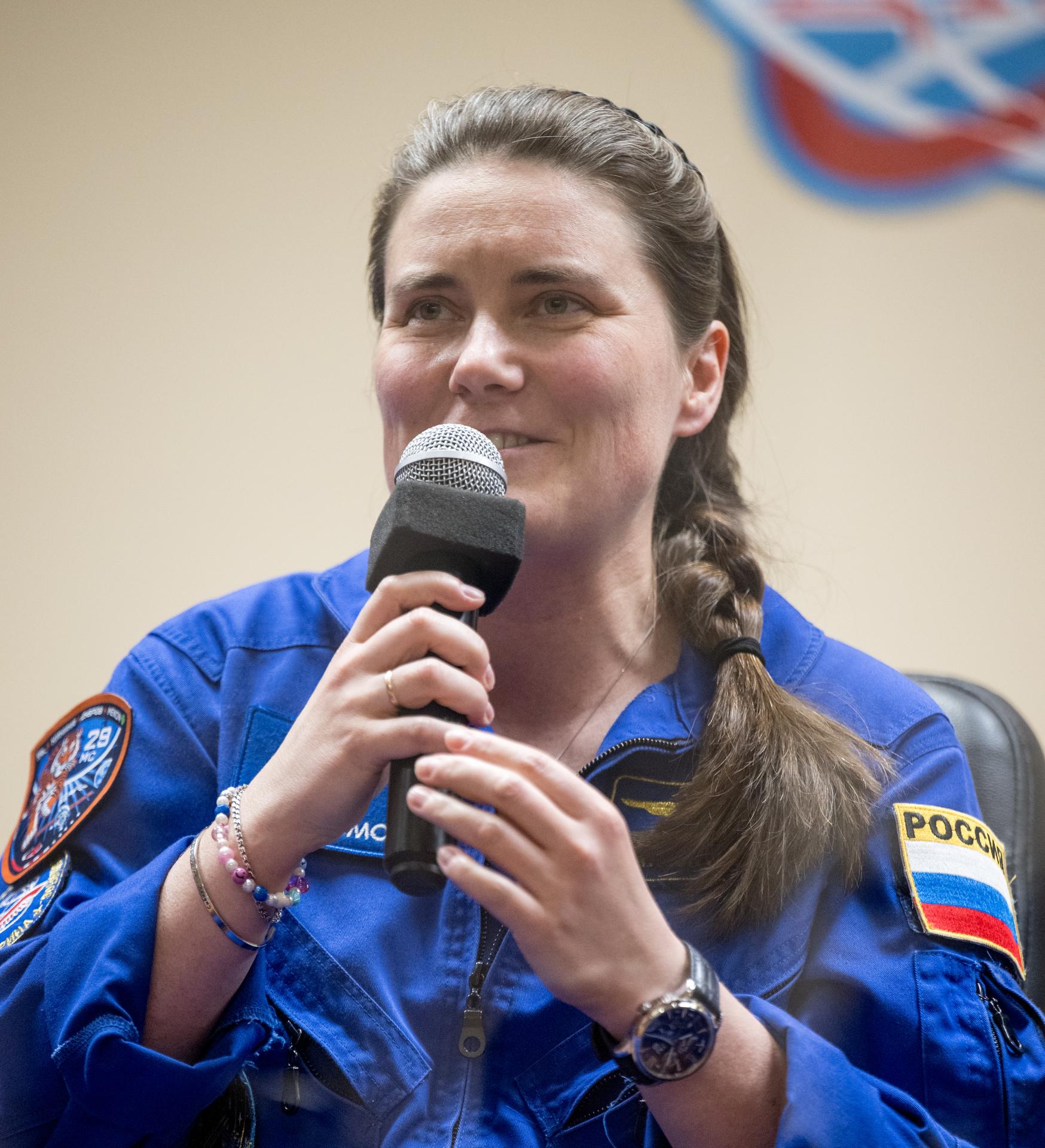 Roscosmos cosmonaut Anna Kikina is seen in quarantine, behind glass, during a press conference, Monday, July 13, 2026 a the Cosmonaut Hotel in Baikonur, Kazakhstan. Expedition 75 crewmembers: NASA astronaut Anil Menon, Roscosmos cosmonauts Pyotr Dubrov and Anna Kikina are scheduled to launch aboard the Soyuz MS-29 spacecraft to the International Space Station on July 14. Photo Credit: (NASA/Bill Ingalls)
