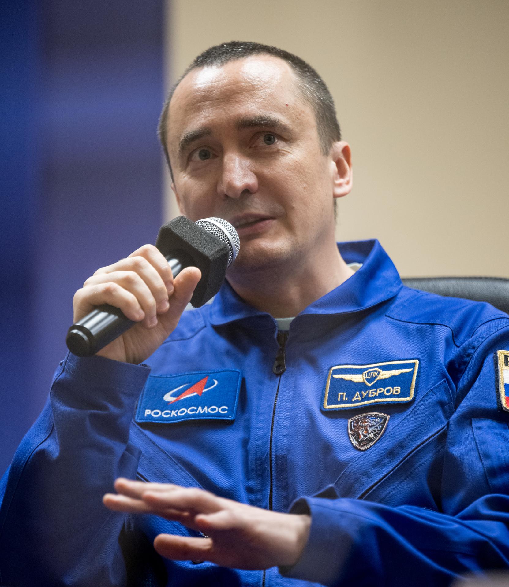 Roscosmos cosmonaut Pyotr Dubrov is seen in quarantine, behind glass, during a press conference, Monday, July 13, 2026 a the Cosmonaut Hotel in Baikonur, Kazakhstan. Expedition 75 crewmembers: NASA astronaut Anil Menon, Roscosmos cosmonauts Pyotr Dubrov and Anna Kikina are scheduled to launch aboard the Soyuz MS-29 spacecraft to the International Space Station on July 14. Photo Credit: (NASA/Bill Ingalls)