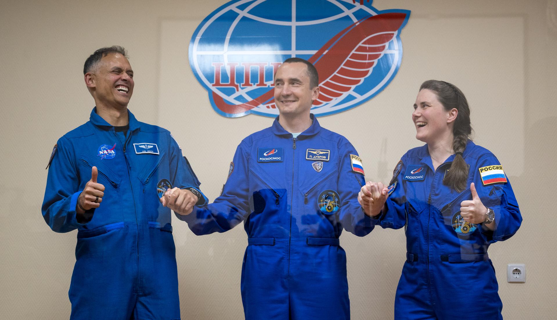 Expedition 75 crewmembers: NASA astronaut Anil Menon, left, Roscosmos cosmonauts Pyotr Dubrov, and Anna Kikina, right, are seen in quarantine, behind glass, during a press conference, Monday, July 13, 2026 a the Cosmonaut Hotel in Baikonur, Kazakhstan. Menon, Dubrov, and Kikina are scheduled to launch aboard the Soyuz MS-29 spacecraft to the International Space Station on July 14. Photo Credit: (NASA/Bill Ingalls)