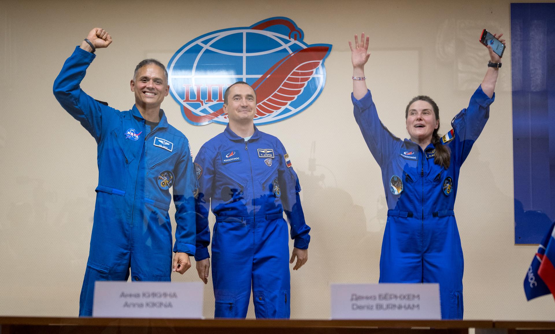 Expedition 75 crewmembers: NASA astronaut Anil Menon, left, Roscosmos cosmonauts Pyotr Dubrov, and Anna Kikina, right, are seen in quarantine, behind glass, during a press conference, Monday, July 13, 2026 a the Cosmonaut Hotel in Baikonur, Kazakhstan. Menon, Dubrov, and Kikina are scheduled to launch aboard the Soyuz MS-29 spacecraft to the International Space Station on July 14. Photo Credit: (NASA/Bill Ingalls)