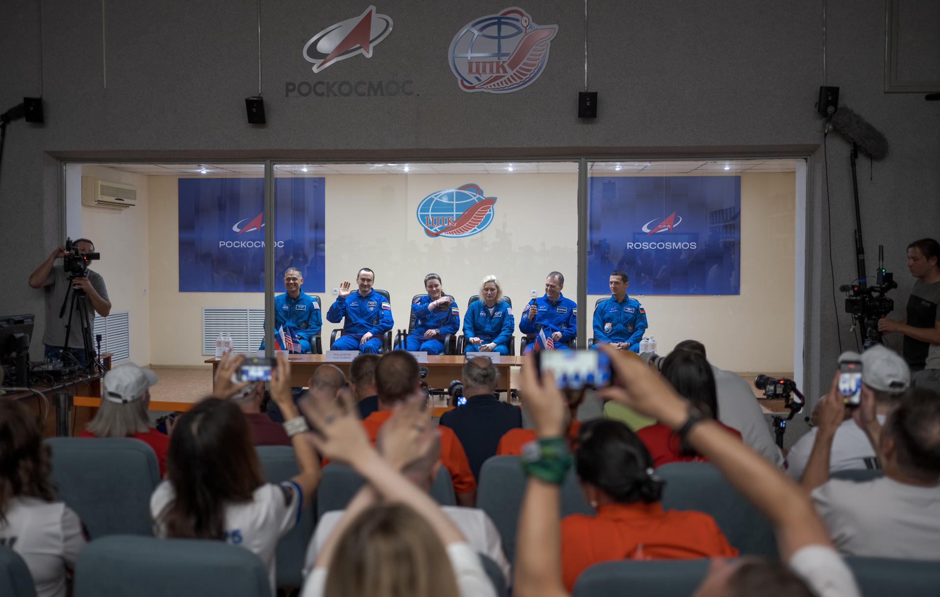 Expedition 75 crewmembers: NASA astronaut Anil Menon, left, Roscosmos cosmonauts Pyotr Dubrov, and Anna Kikina, along with backup crewmemebers: NASA astronaut Deniz Burnham, Roscosmos cosmonauts Dmitry Petelin, and Konstantin Borisov, right, are seen in quarantine, behind glass, during a press conference, Monday, July 13, 2026 a the Cosmonaut Hotel in Baikonur, Kazakhstan. Menon, Dubrov, and Kikina are scheduled to launch aboard the Soyuz MS-29 spacecraft to the International Space Station on July 14. Photo Credit: (NASA/Bill Ingalls)