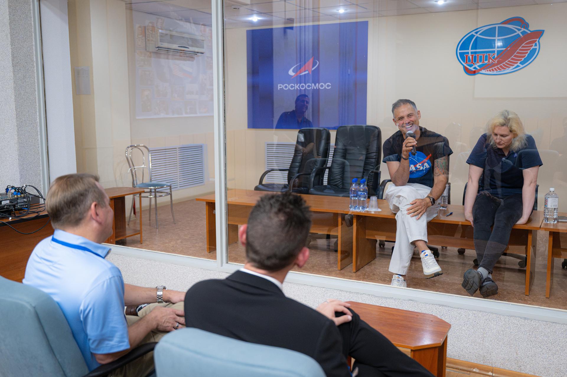NASA Administrator Jared Isaacman, center, and NASA Deputy Administrator Matt Anderson, left, listen as NASA astronaut and Expedition 75 crewmember Anil Menon, third from left, and Deniz Burnham, Expedition 75 backup crewmember, right, speak from quarantine, Monday, July 13, 2026, at the Cosmonaut Hotel in Baikonur, Kazakhstan. Expedition 75 crewmembers NASA astronaut Anil Menon and Roscosmos cosmonauts Pyotr Dubrov and Anna Kikina are scheduled to launch aboard the Soyuz MS-29 spacecraft to the International Space Station on July 14. Photo Credit: (NASA/John Kraus)