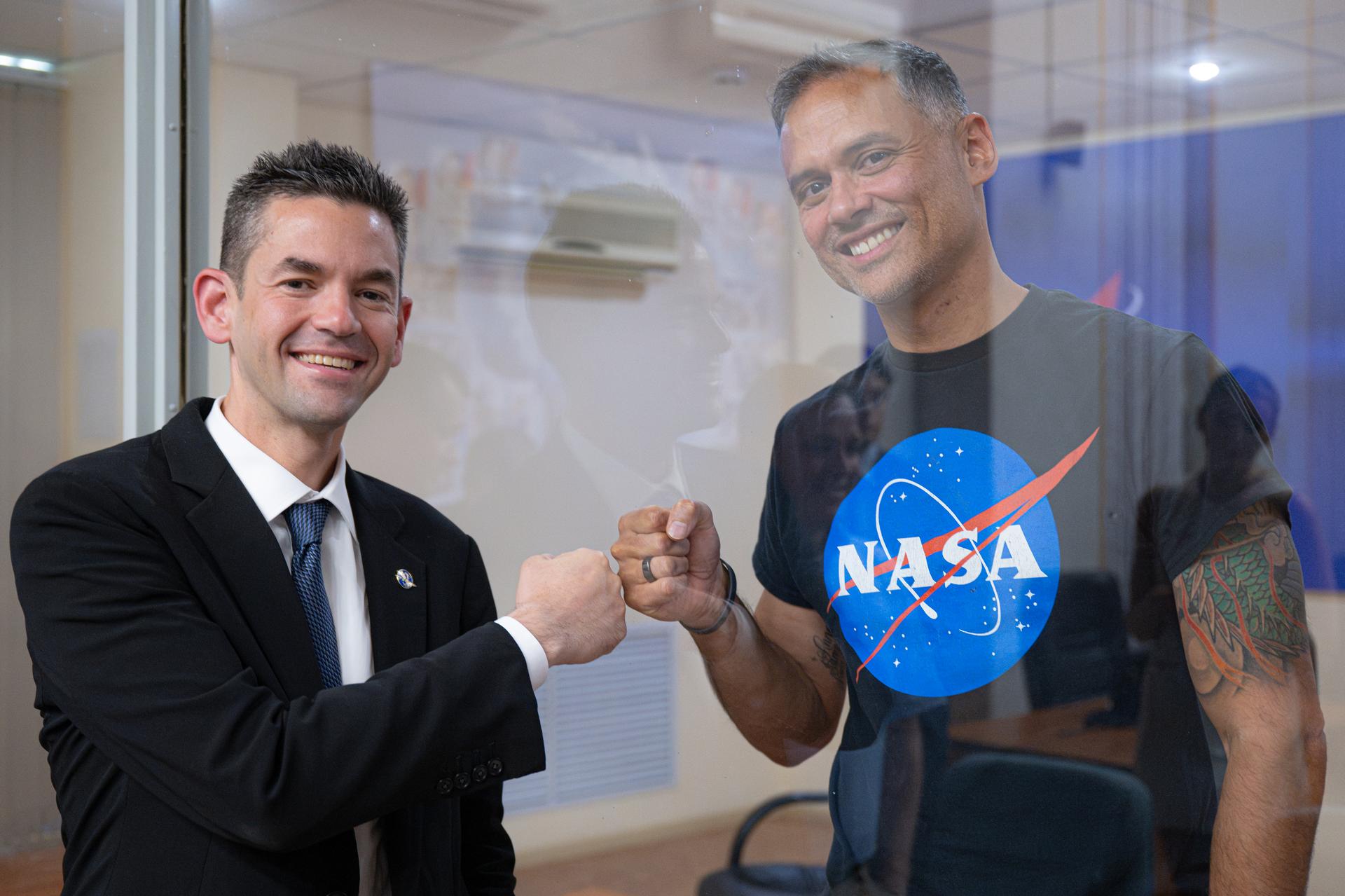 NASA Administrator Jared Isaacman, left, and NASA astronaut and Expedition 75 crewmember Anil Menon, right, pose for a photograph between glass, Monday, July 13, 2026, at the Cosmonaut Hotel in Baikonur, Kazakhstan. Expedition 75 crewmembers NASA astronaut Anil Menon and Roscosmos cosmonauts Pyotr Dubrov and Anna Kikina are scheduled to launch aboard the Soyuz MS-29 spacecraft to the International Space Station on July 14. Photo Credit: (NASA/John Kraus)
