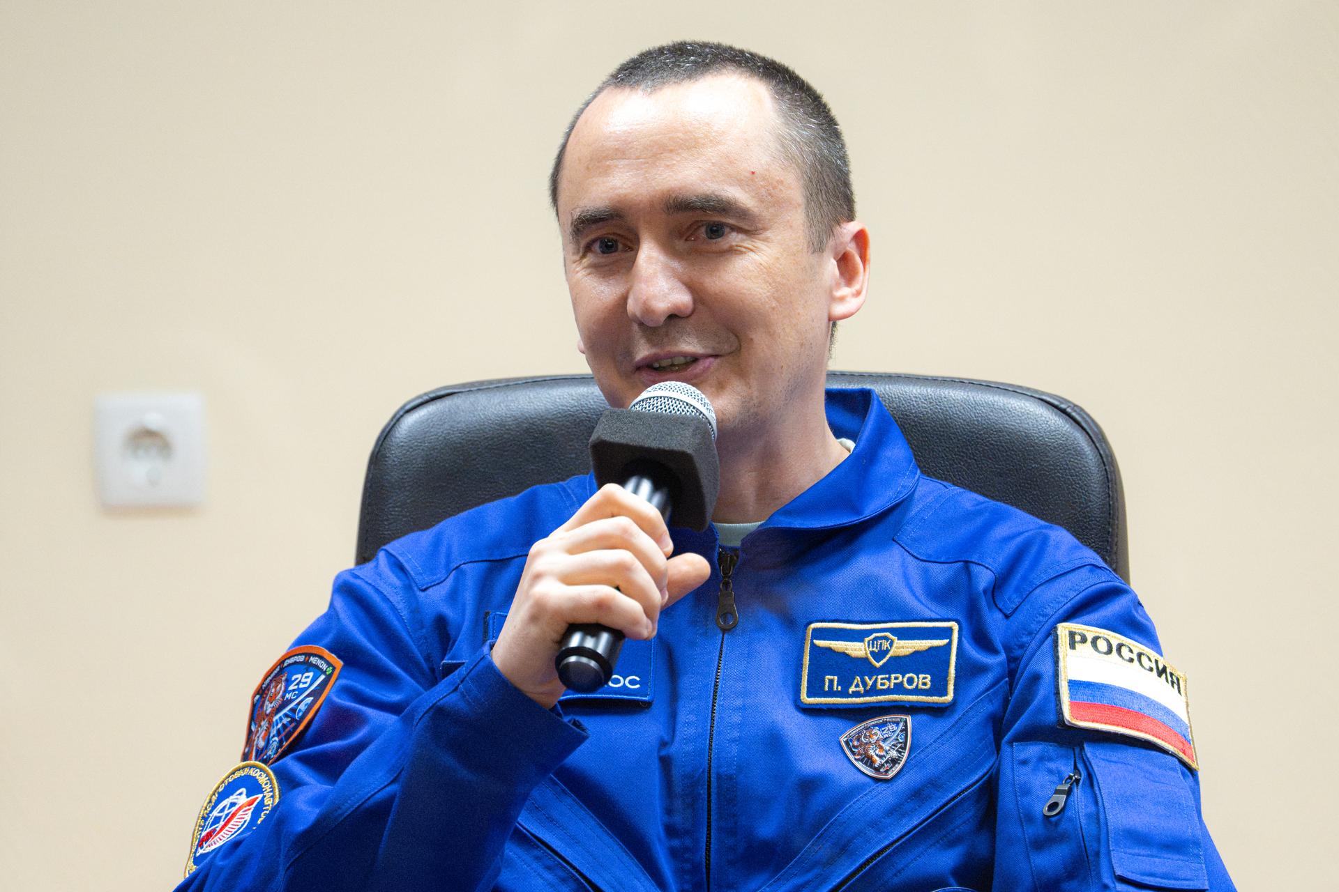 Expedition 75 crewmember Pyotr Dubrov of Roscosmos is seen in quarantine, behind glass, during a press conference, Monday, July 13, 2026, at the Cosmonaut Hotel in Baikonur, Kazakhstan. Expedition 75 crewmembers NASA astronaut Anil Menon and Roscosmos cosmonauts Pyotr Dubrov and Anna Kikina are scheduled to launch aboard the Soyuz MS-29 spacecraft to the International Space Station on July 14. Photo Credit: (NASA/John Kraus)