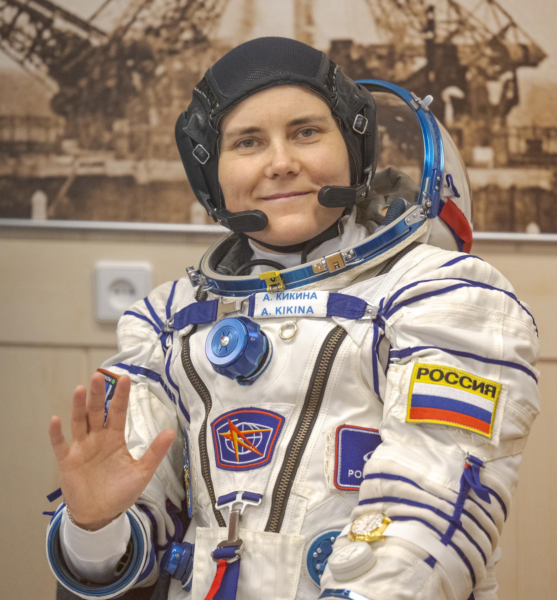 Roscosmos cosmonaut Anna Kikina waves while waiting to have her Russian Sokol Suit pressure checked, as she and fellow crewmates, Roscosmos cosmonaut Pyotr Dubrov, and NASA astronaut Anil Menon, prepare for their Soyuz launch to the International Space Station Tuesday, July 14, 2026 in Baikonur, Kazakhstan. Photo Credit: (NASA/Bill Ingalls)