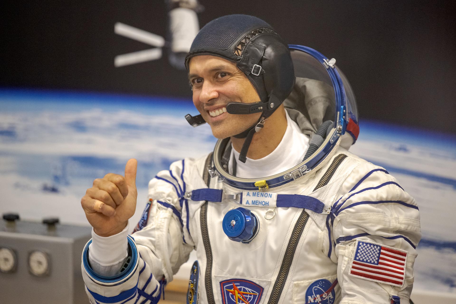 NASA astronaut Anil Menon gestures to family and friends while waiting to have his Russian Sokol Suit pressure checked, as he and fellow crewmates, Roscosmos cosmonauts Pyotr Dubrov, and Anna Kikina, prepare for their Soyuz launch to the International Space Station Tuesday, July 14, 2026 in Baikonur, Kazakhstan. Photo Credit: (NASA/Bill Ingalls)