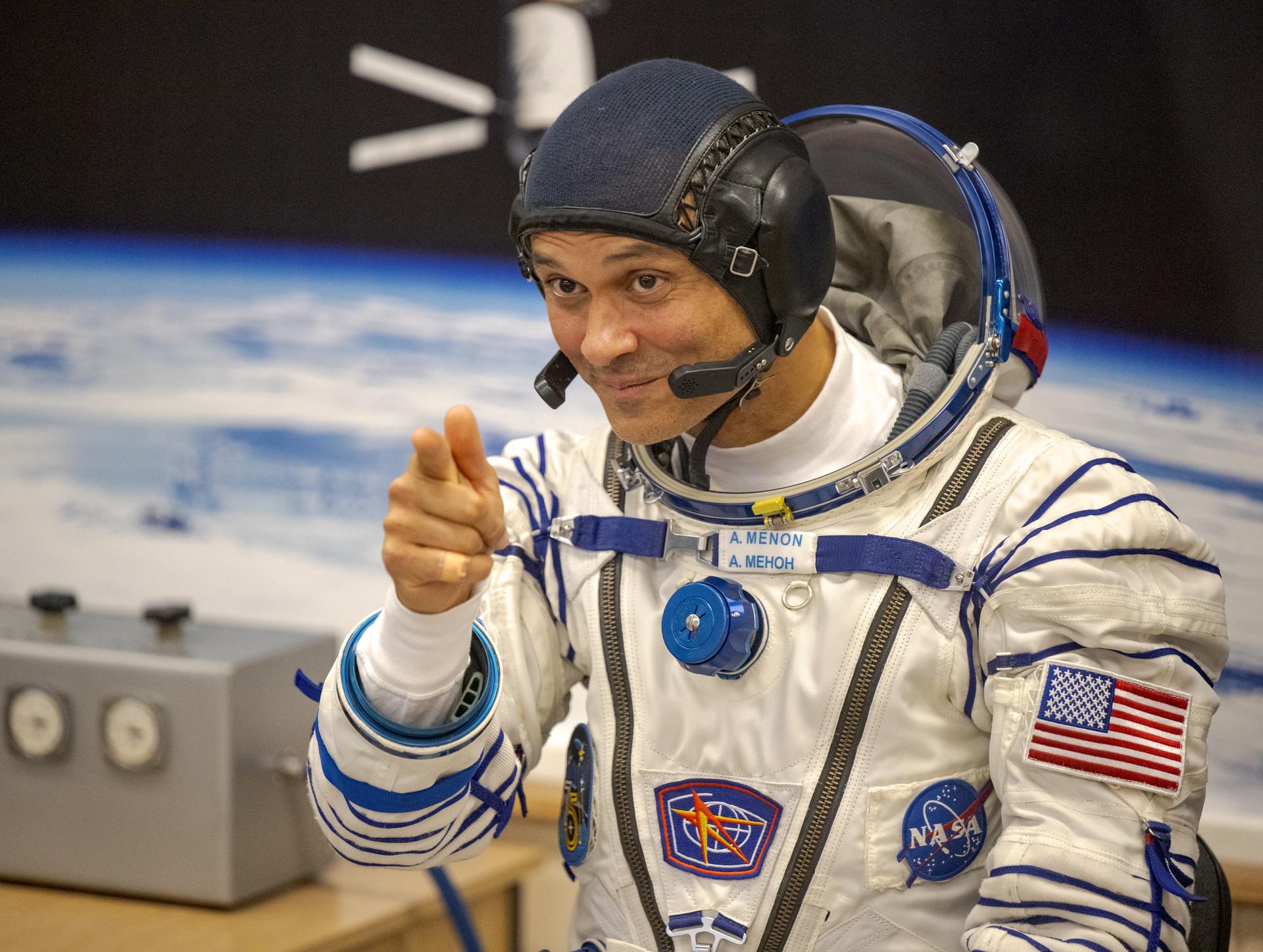 NASA astronaut Anil Menon gestures to family and friends while waiting to have his Russian Sokol Suit pressure checked, as he and fellow crewmates, Roscosmos cosmonauts Pyotr Dubrov, and Anna Kikina, prepare for their Soyuz launch to the International Space Station Tuesday, July 14, 2026 in Baikonur, Kazakhstan. Photo Credit: (NASA/Bill Ingalls)