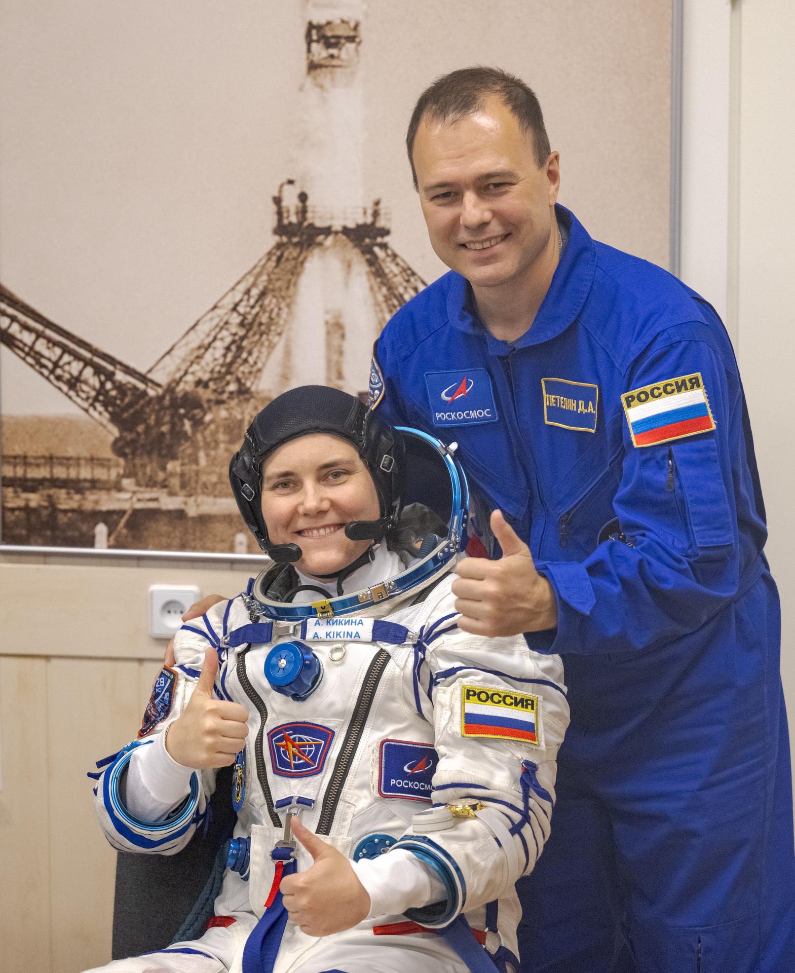 Roscosmos cosmonaut Anna Kikina and backup crew member Roscosmos cosmonaut Dmitry Petelin give a thumbs up while Kikina waits to have her Russian Sokol Suit pressure checked, as she and fellow crewmates, Roscosmos cosmonaut Pyotr Dubrov, and NASA astronaut Anil Menon, prepare for their Soyuz launch to the International Space Station Tuesday, July 14, 2026 in Baikonur, Kazakhstan. Photo Credit: (NASA/Bill Ingalls)