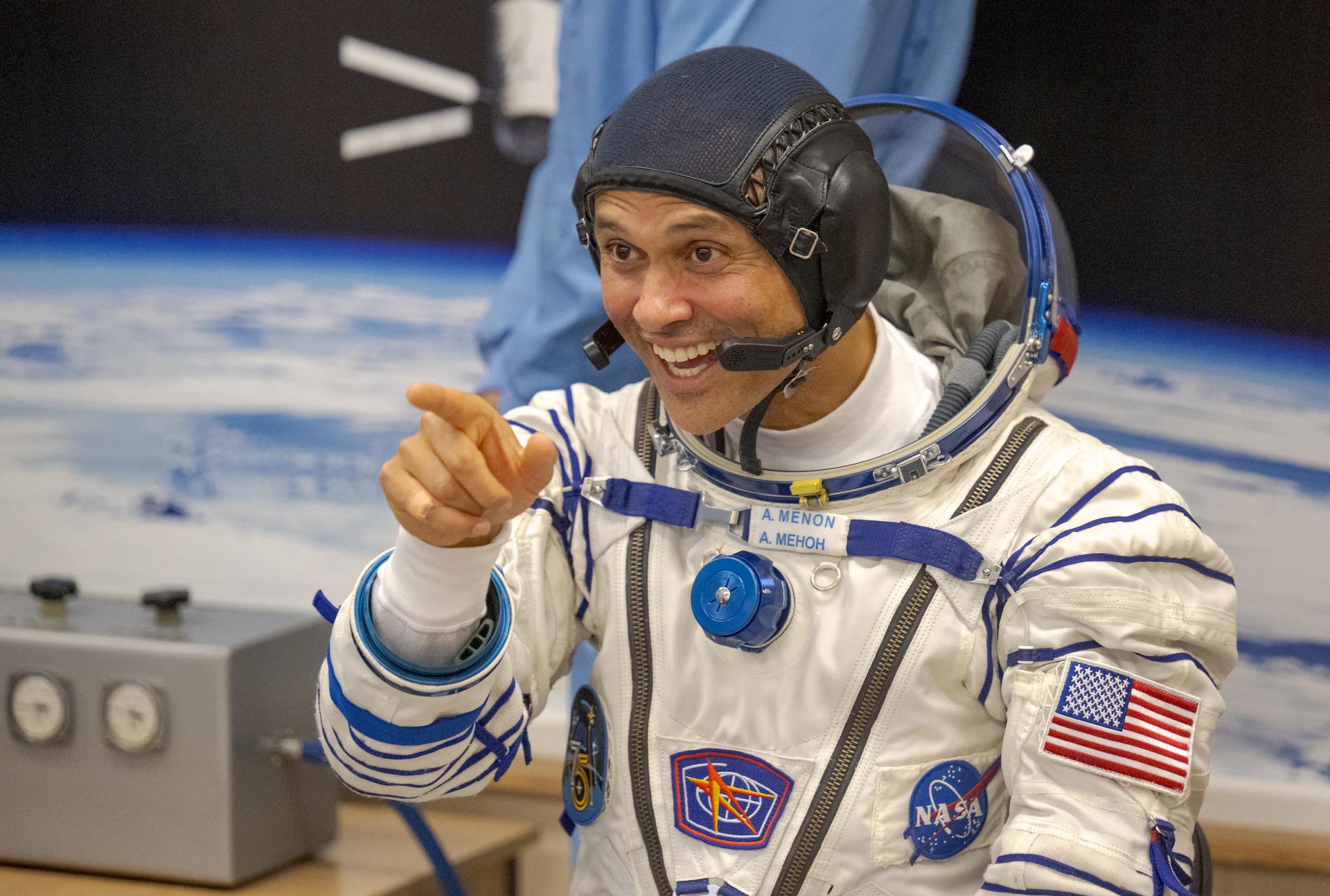 NASA astronaut Anil Menon gestures to family and friends while waiting to have his Russian Sokol Suit pressure checked, as he and fellow crewmates, Roscosmos cosmonauts Pyotr Dubrov, and Anna Kikina, prepare for their Soyuz launch to the International Space Station Tuesday, July 14, 2026 in Baikonur, Kazakhstan. Photo Credit: (NASA/Bill Ingalls)