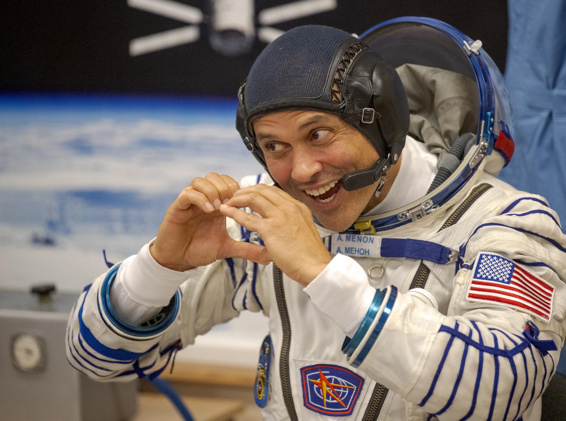 NASA astronaut Anil Menon gestures to family and friends while waiting to have his Russian Sokol Suit pressure checked, as he and fellow crewmates, Roscosmos cosmonauts Pyotr Dubrov, and Anna Kikina, prepare for their Soyuz launch to the International Space Station Tuesday, July 14, 2026 in Baikonur, Kazakhstan. Photo Credit: (NASA/Bill Ingalls)