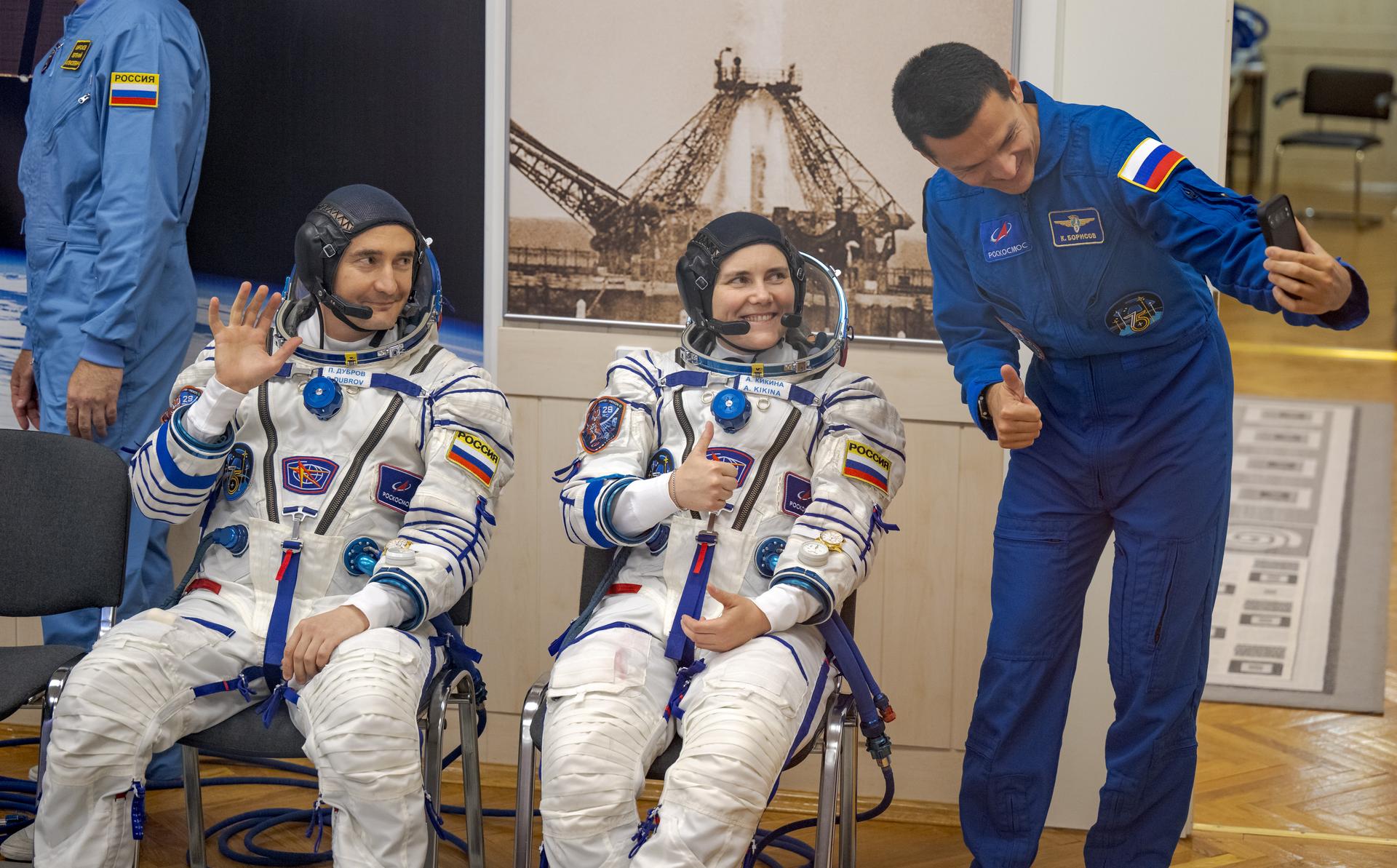 Expedition 75 Roscosmos cosmonauts Pyotr Dubrov, left, and Anna Kikina, smile for a selfie taken by Expedition 75 backup crew member Konstantin Borisov of Roscosmos, as the crew has their Russian Sokol Suits pressure checked with fellow crewmate, NASA astronaut Anil Menon, and they prepare for their Soyuz launch to the International Space Station Tuesday, July 14, 2026 in Baikonur, Kazakhstan. Photo Credit: (NASA/Bill Ingalls)