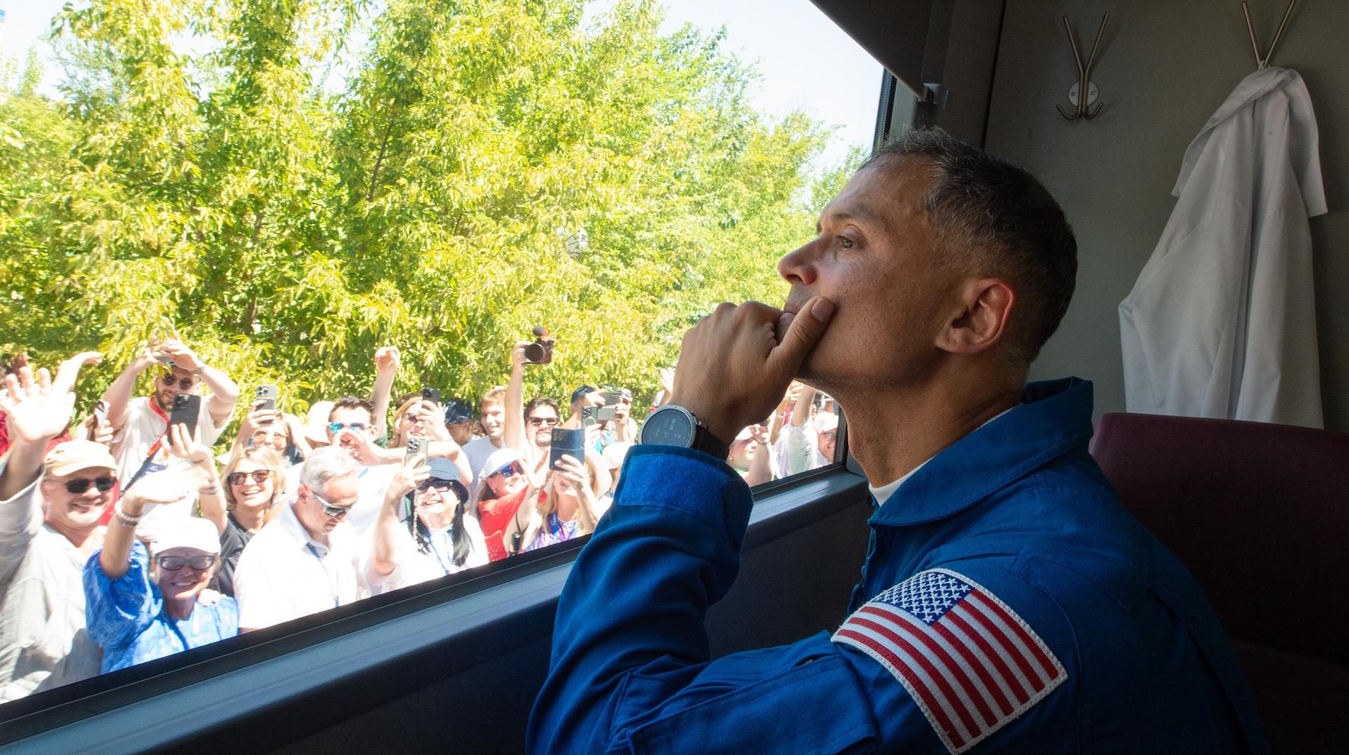 Expedition 75 NASA astronaut Anil Menon looks out the bus window as he departs the Cosmonaut Hotel with crew mates Roscosmos cosmonauts Anna Kikina, and Pyotr Dubrov, to suit-up for their Soyuz launch, Tuesday, July 14, 2026, in Baikonur, Kazakhstan. The launch will send Menon, Dubrov, and Kikina on a mission to the International Space Station. Photo Credit: (NASA/GCTC/Pavel Shvets)
