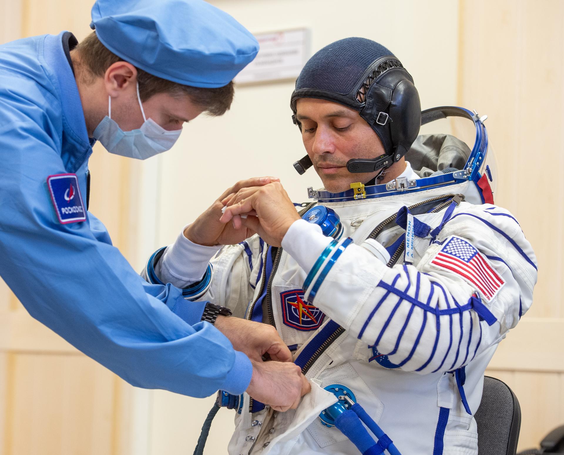 Expedition 75 NASA astronaut Anil Menon is helped into his Russian Sokol suit as he and fellow crew mates, Roscosmos cosmonauts Pyotr Dubrov, and Anna Kikina, prepare for their Soyuz launch to the International Space Station Tuesday, July 14, 2026 in Baikonur, Kazakhstan. The launch will send Menon, Dubrov, and Kikina on a mission to the International Space Station. Photo Credit: (NASA/GCTC/Pavel Shvets)