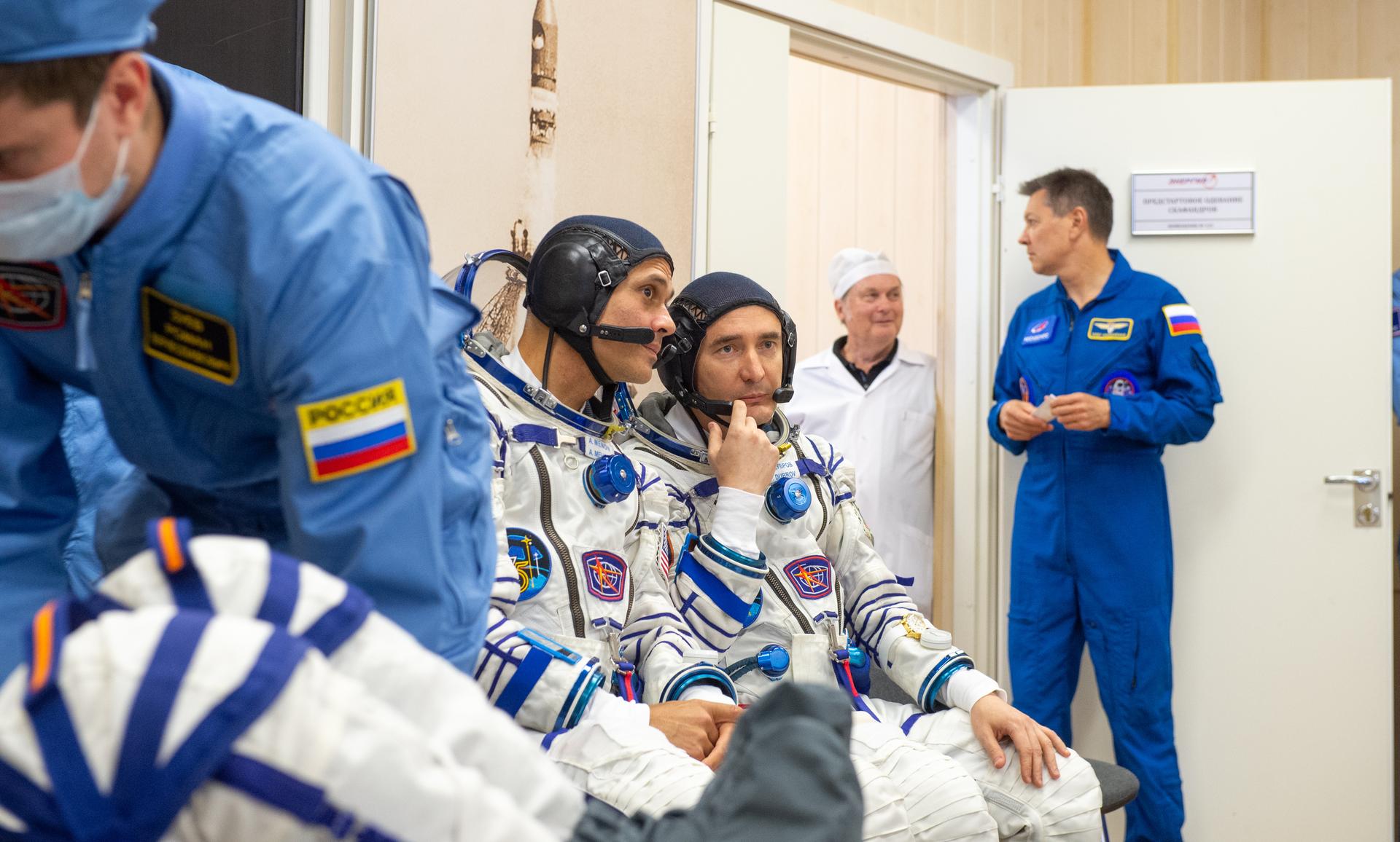 Expedition 75 NASA astronaut Anil Menon, left, and Roscosmos cosmonaut Pyotr Dubrov, talk as they and Roscosmos cosmonaut Anna Kikina have their Russian Sokol suits pressure checked for their Soyuz launch to the International Space Station Tuesday, July 14, 2026 in Baikonur, Kazakhstan. Photo Credit: (NASA/GCTC/Pavel Shvets)